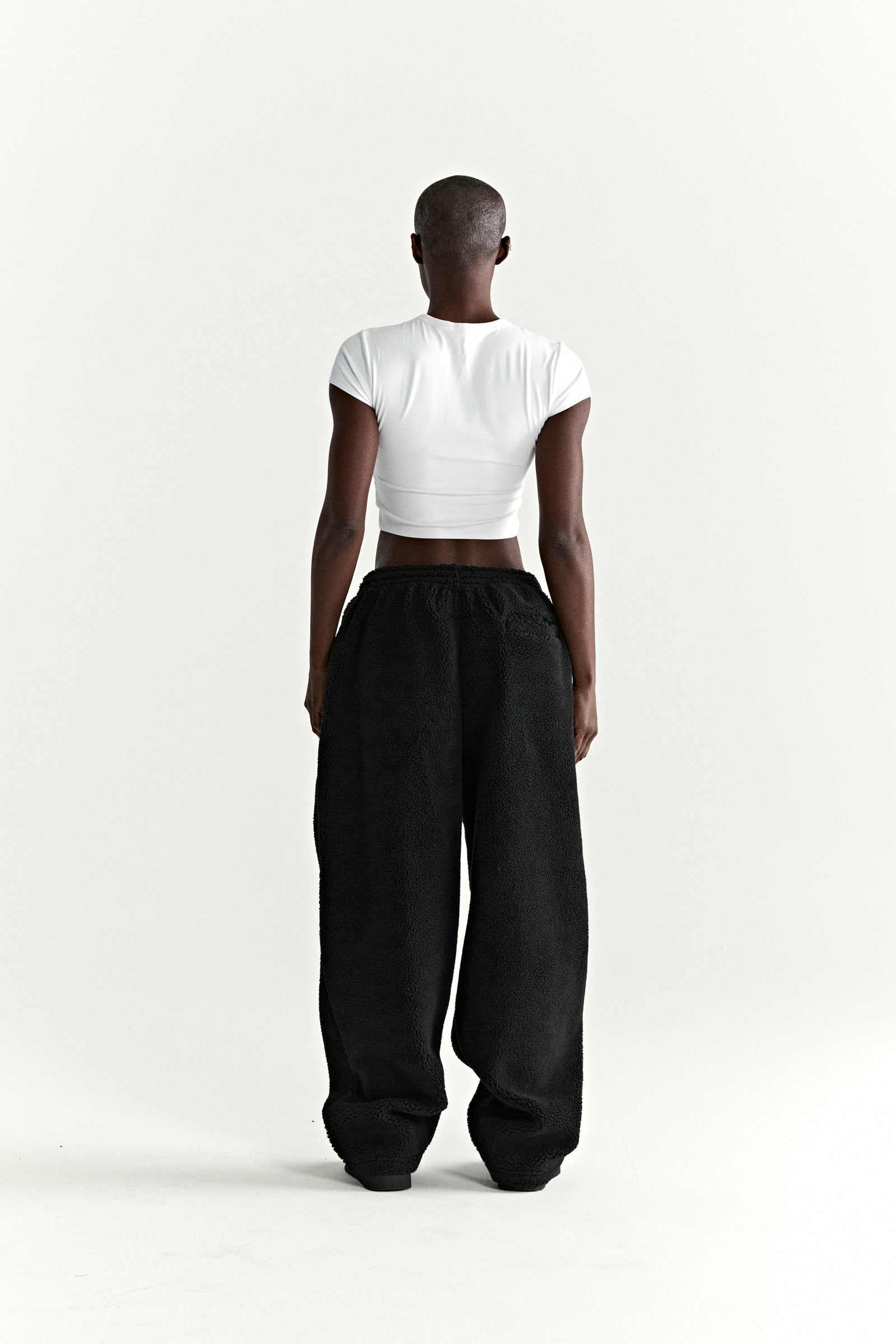 Black teddy fleece pants with a straight leg fit, elasticized waistband, and rubberized logo patch.