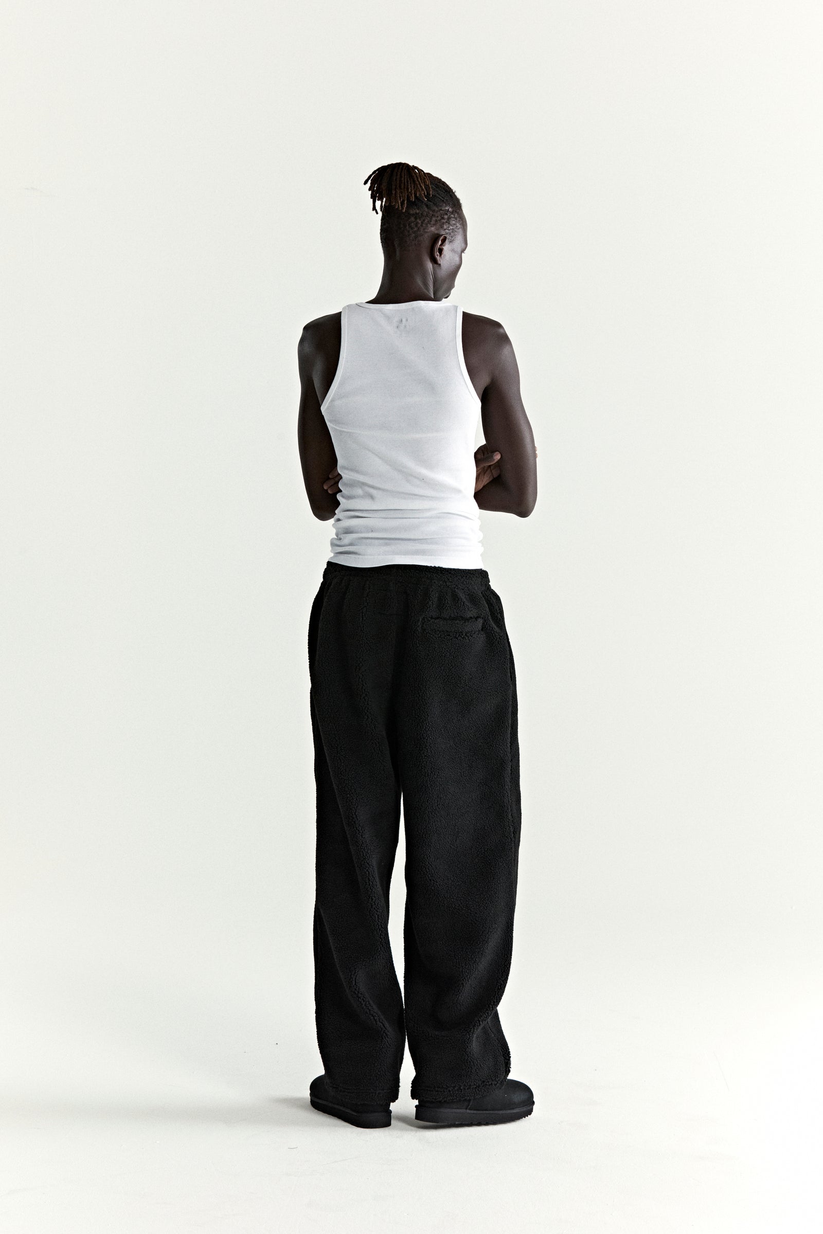 Model from behind wearing black TEDDY FLEECE PANT, a sherpa fleece pant with a straight leg fit.