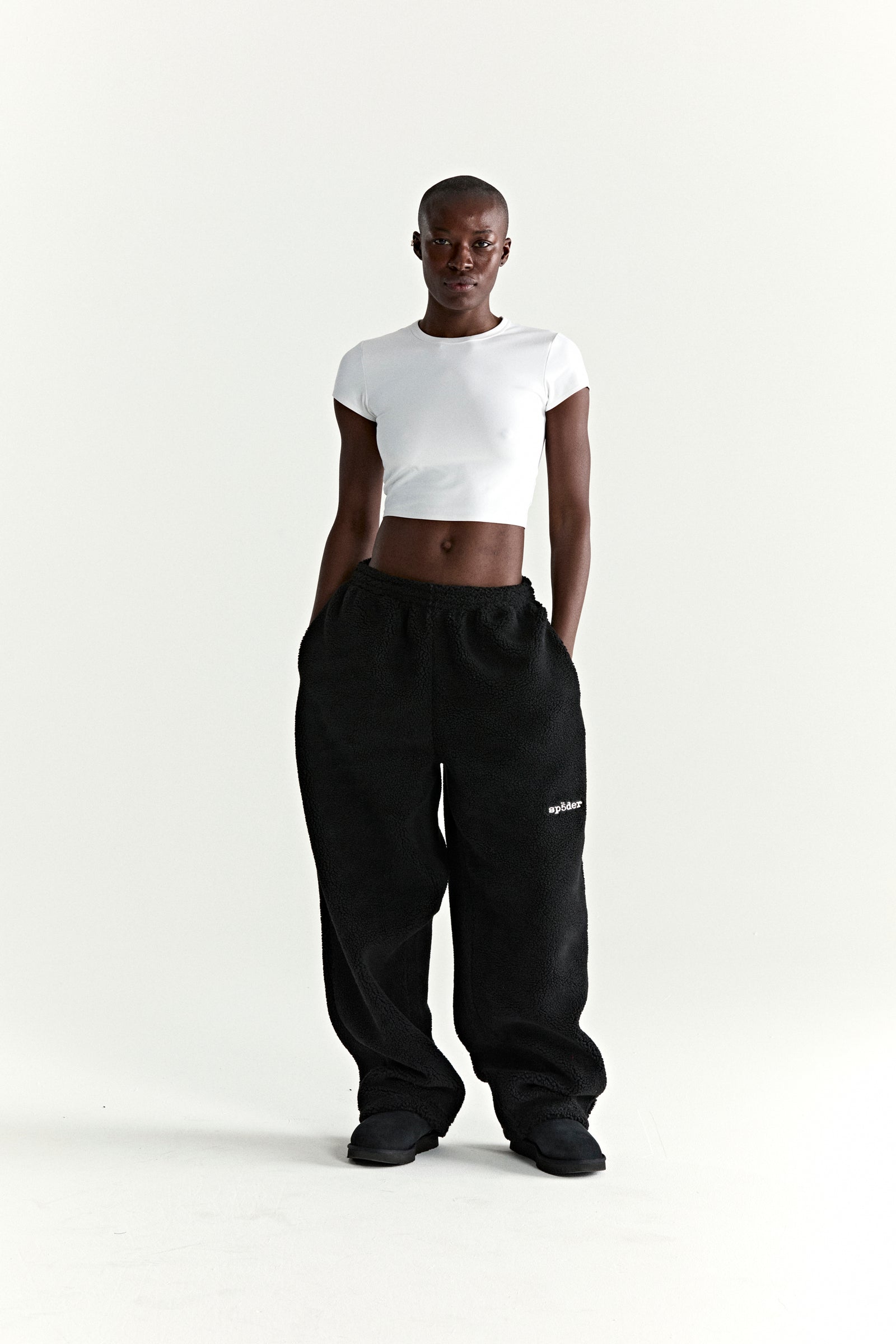 Black teddy fleece pants with white logo patch, elasticized drawstring waist, and straight leg fit.