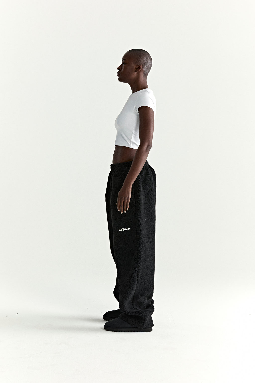 Black teddy fleece pant with rubberized logo patch on leg, worn by a model.