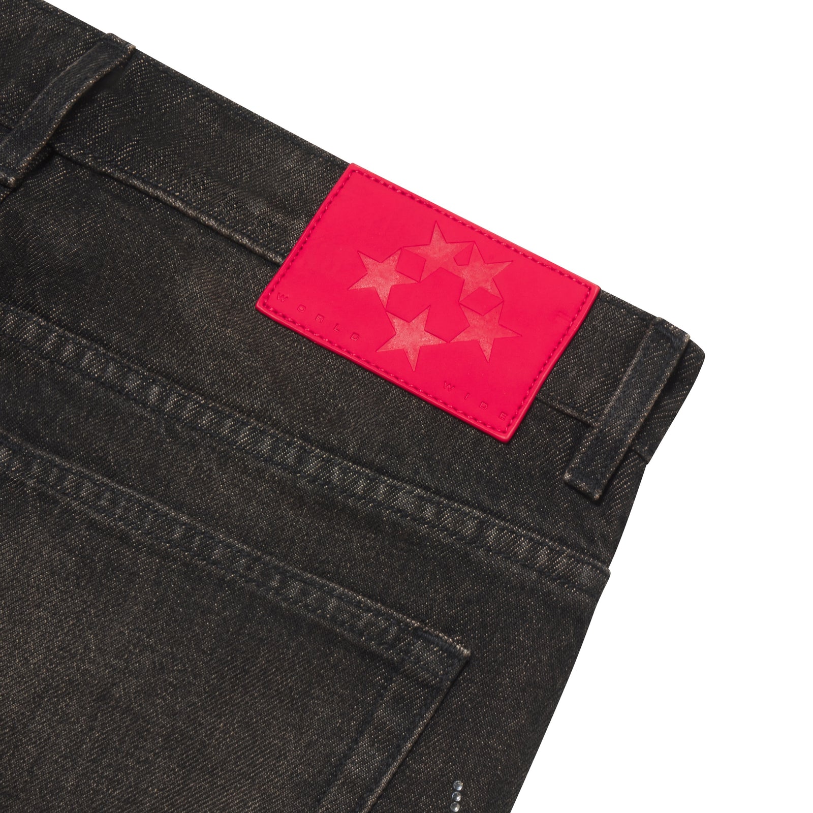 Faded black 13oz denim jeans featuring a bright red branded leather back patch with a star graphic design.