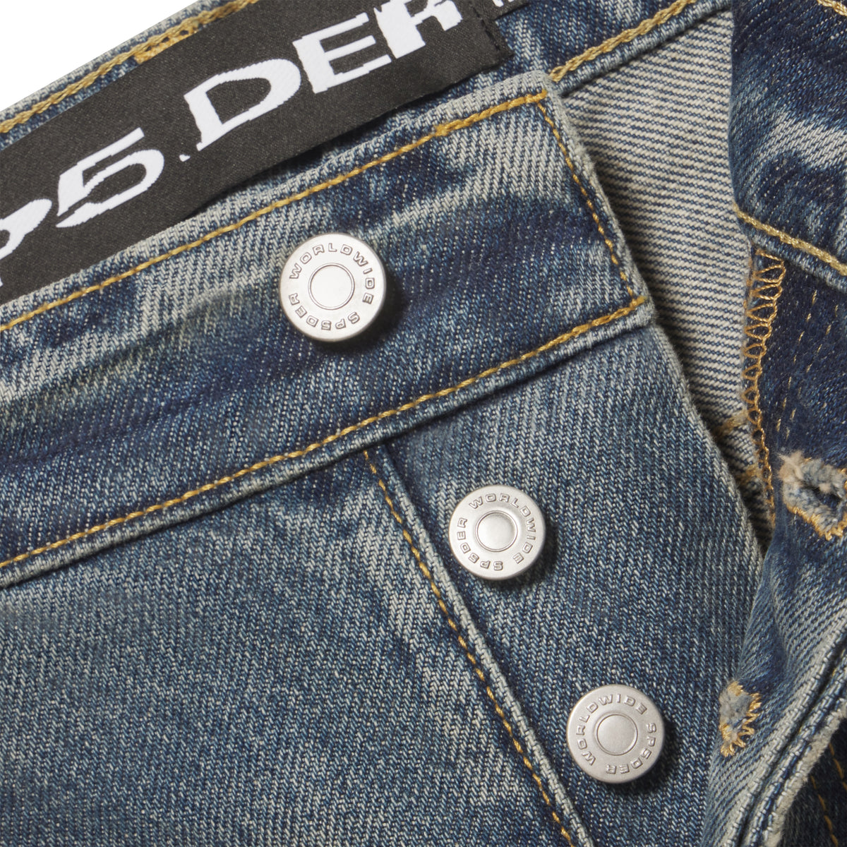 Faded blue denim jeans featuring branded silver shank buttons and a black leather patch at the waist.