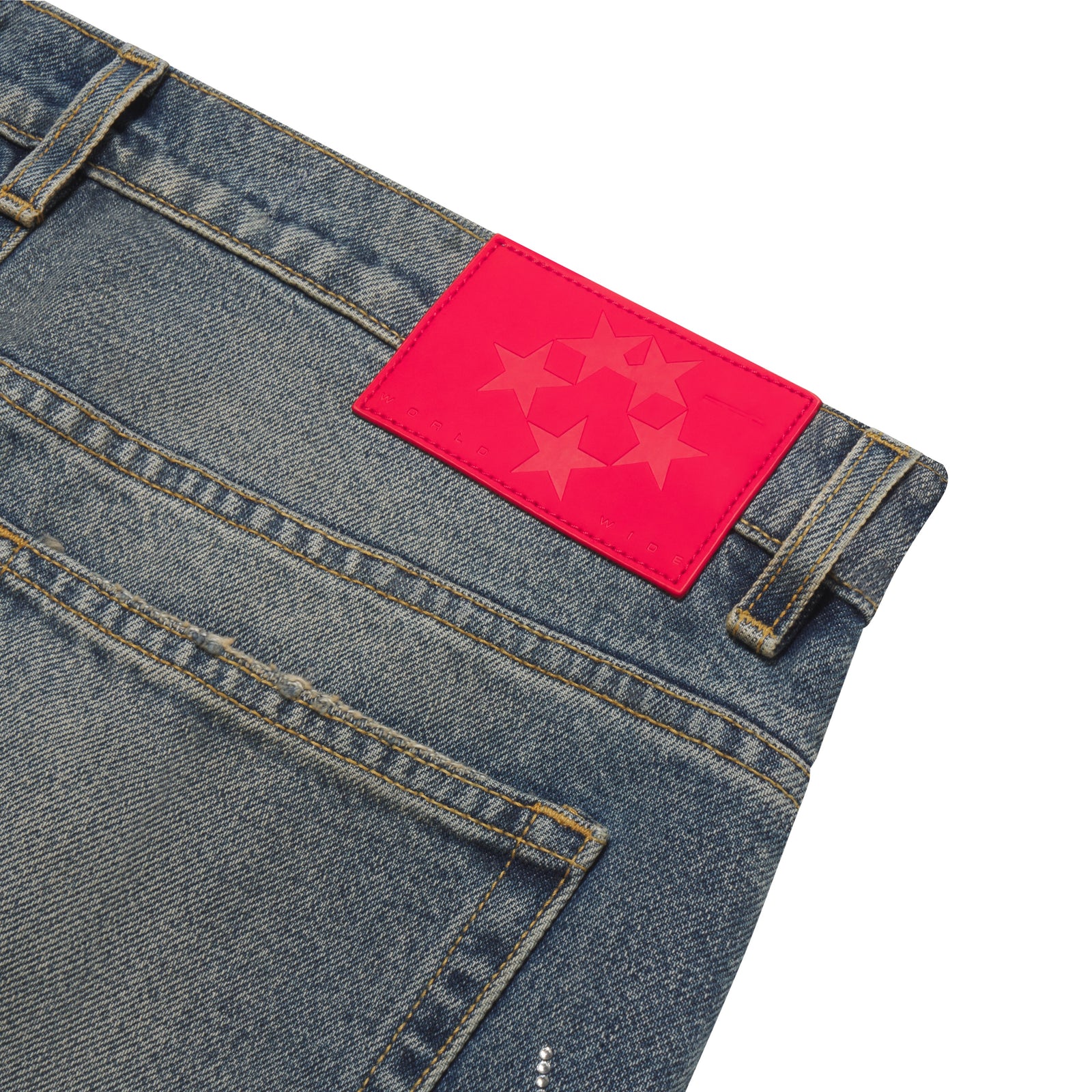 Faded blue denim jeans featuring a bright pink branded leather patch with a star graphic design and rhinestone details.