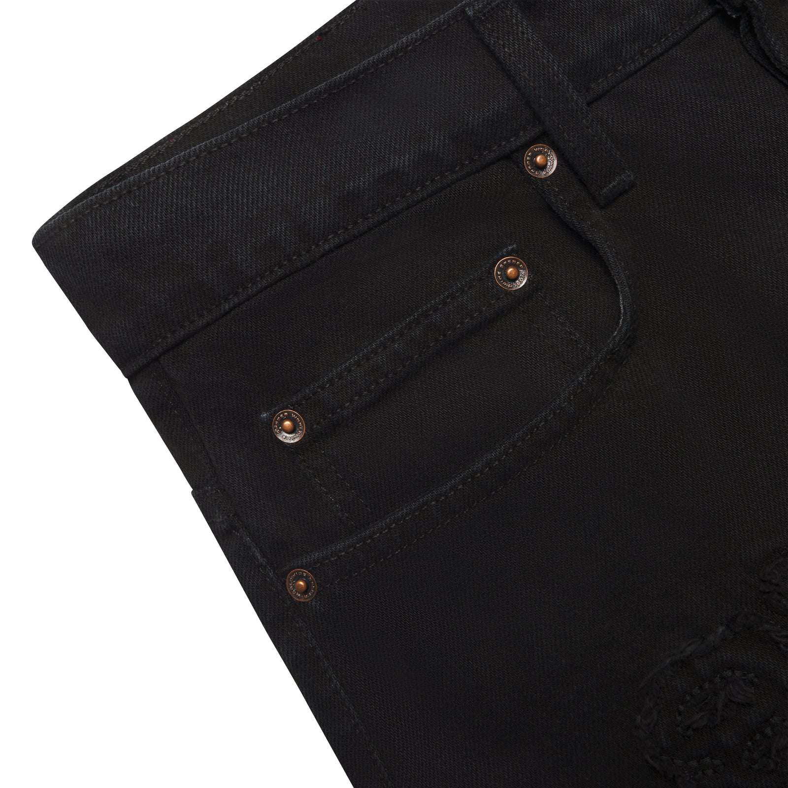 Close-up of black distressed denim jeans with custom branded hardware and frayed embroidered logo.