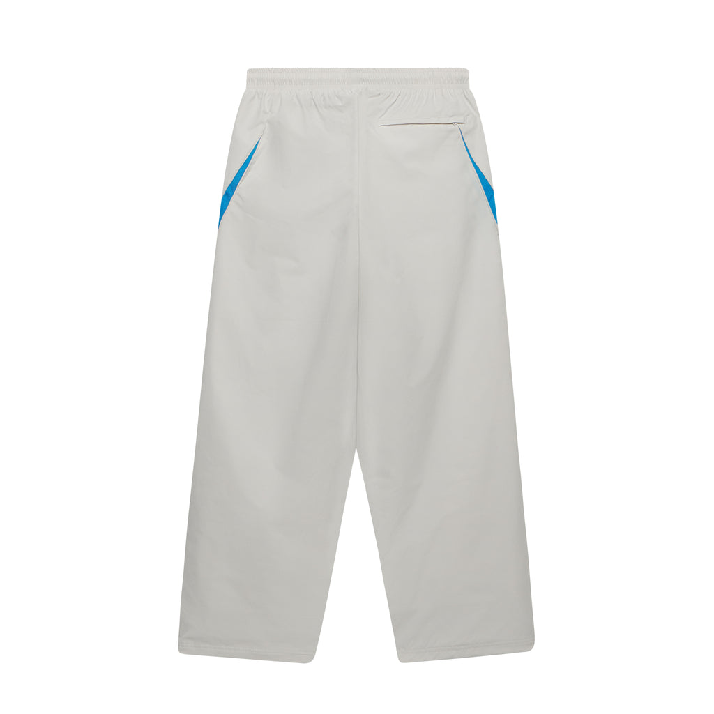 Beige nylon wide-leg track pants featuring blue contrast side panels, an elastic waistband, and a back zip pocket.