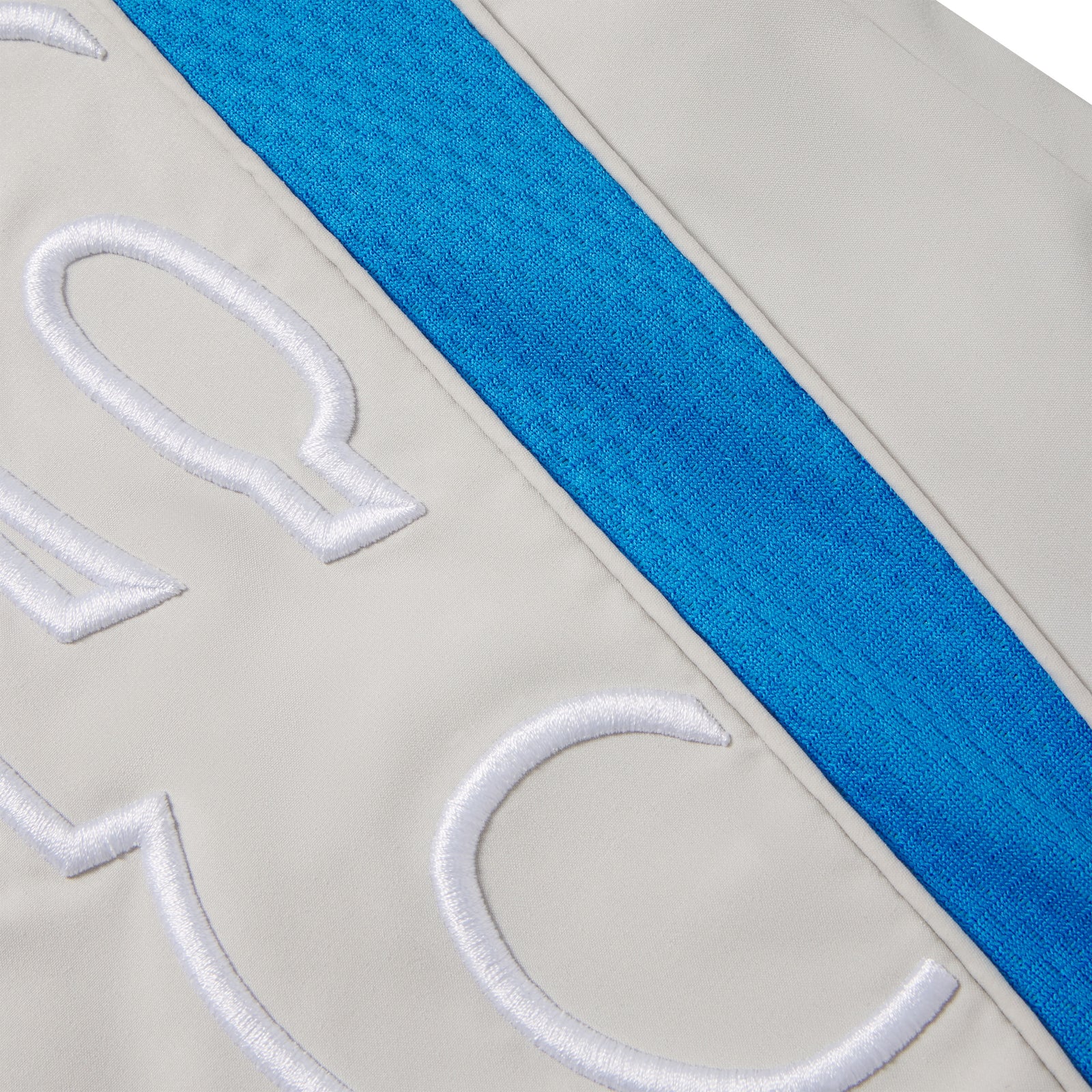 Grey nylon track pant featuring a bright blue mesh side panel and white embroidered graphic text.