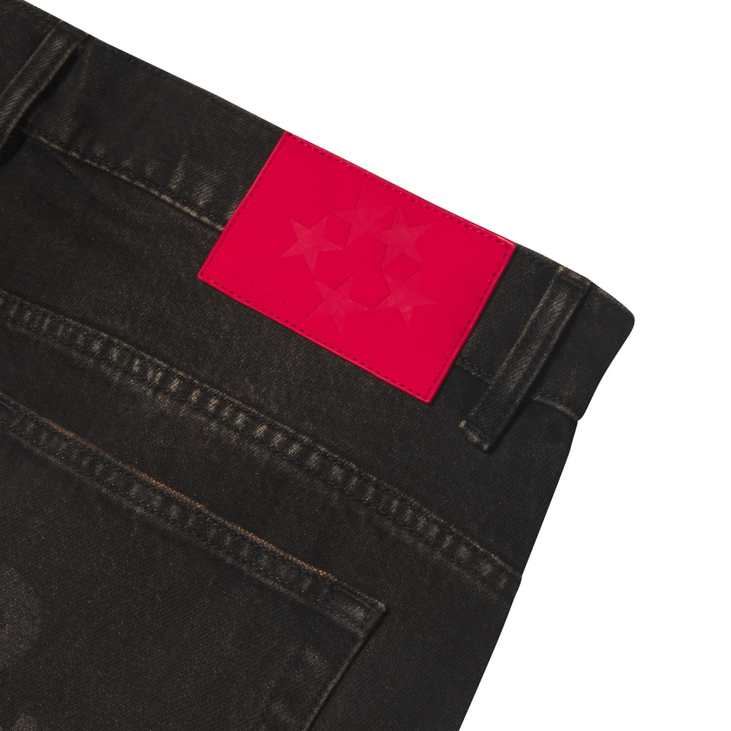 Black denim jeans featuring a bright red leather back patch with a star graphic print and belt loops.
