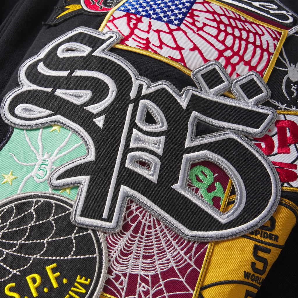 Black cotton fleece zip hoodie featuring an all-over mix of embroidered, woven, and chenille graphic patches.
