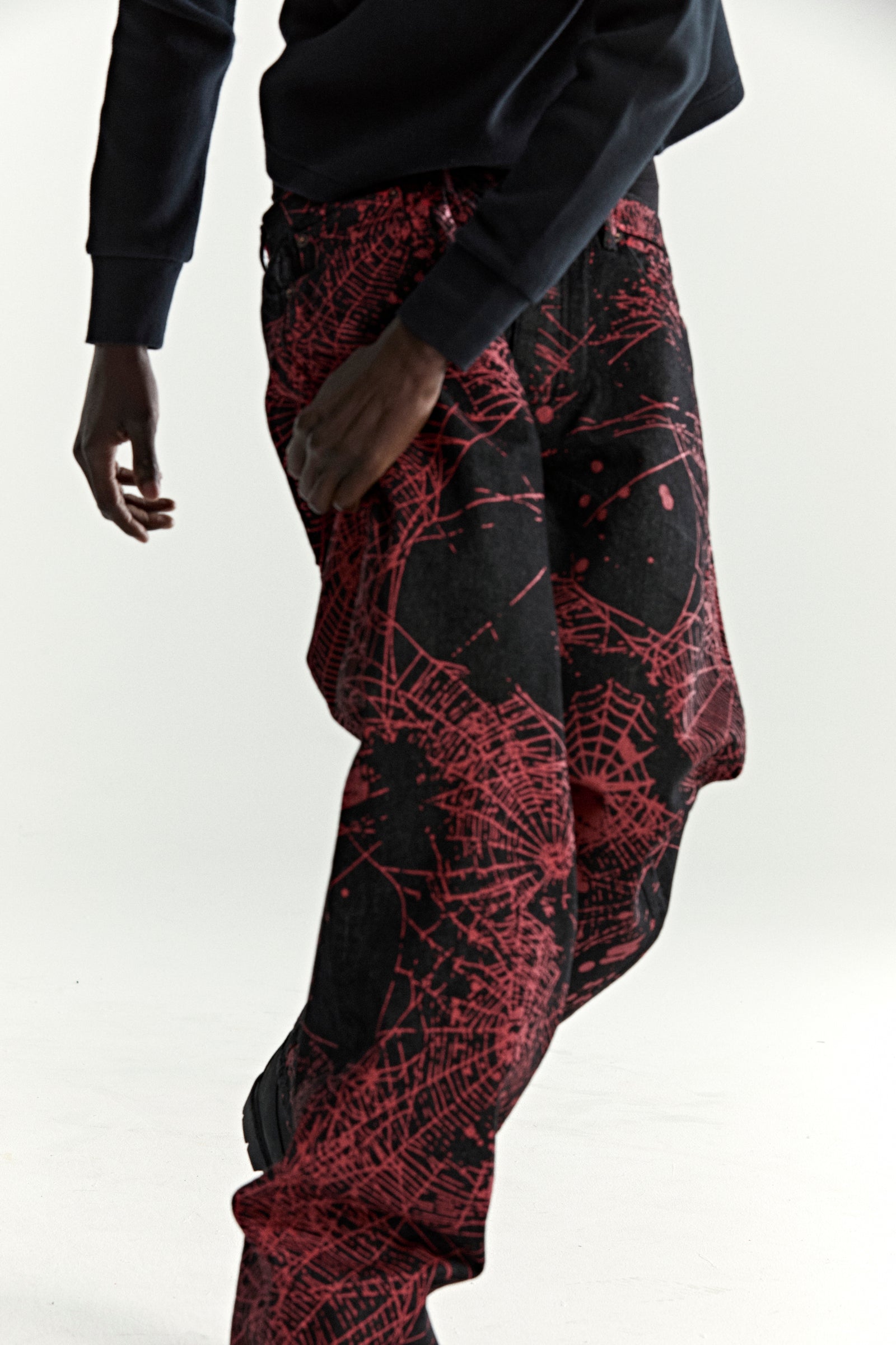 Black V2 WEB DENIM pants with red all-over web print, classic straight leg fit.