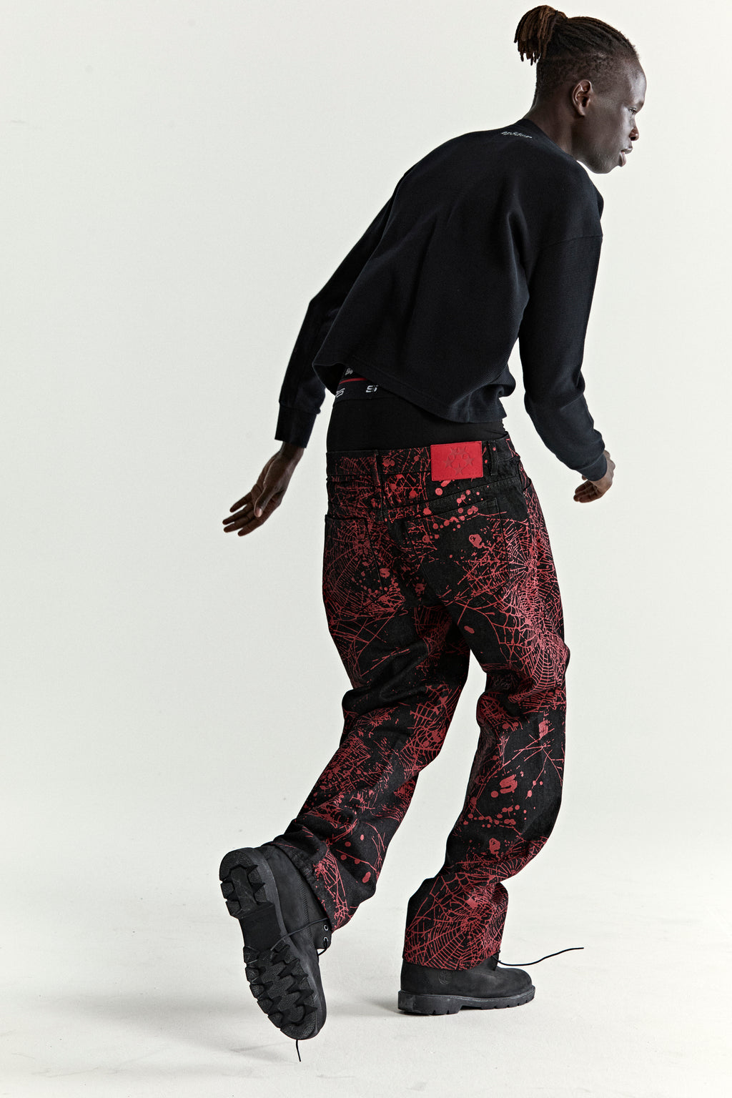 V2 WEB DENIM pants: black denim with red all-over web print, classic straight leg fit, and five-pocket styling.