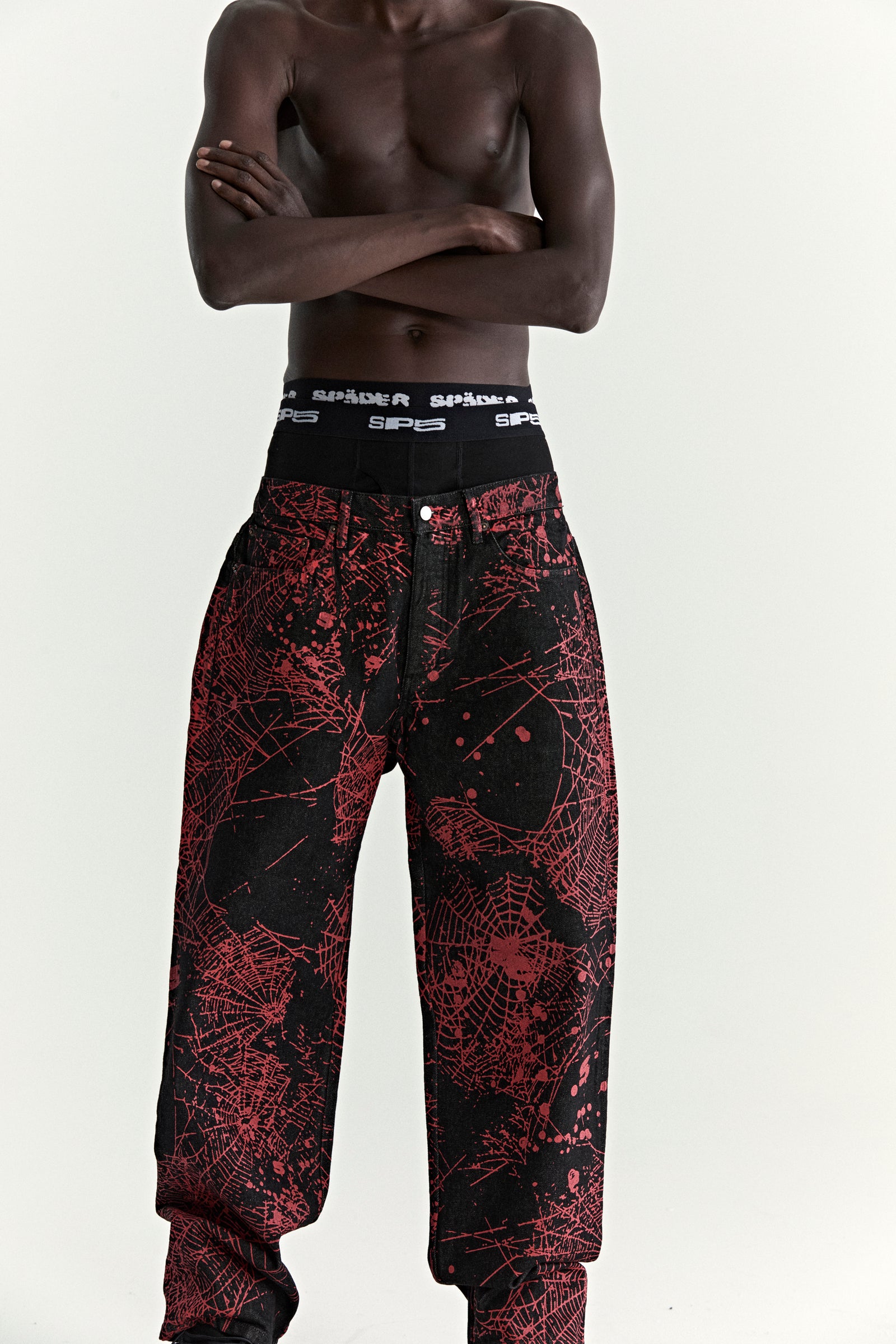 Black denim pants with all-over red web print, five-pocket styling, and a straight leg fit.