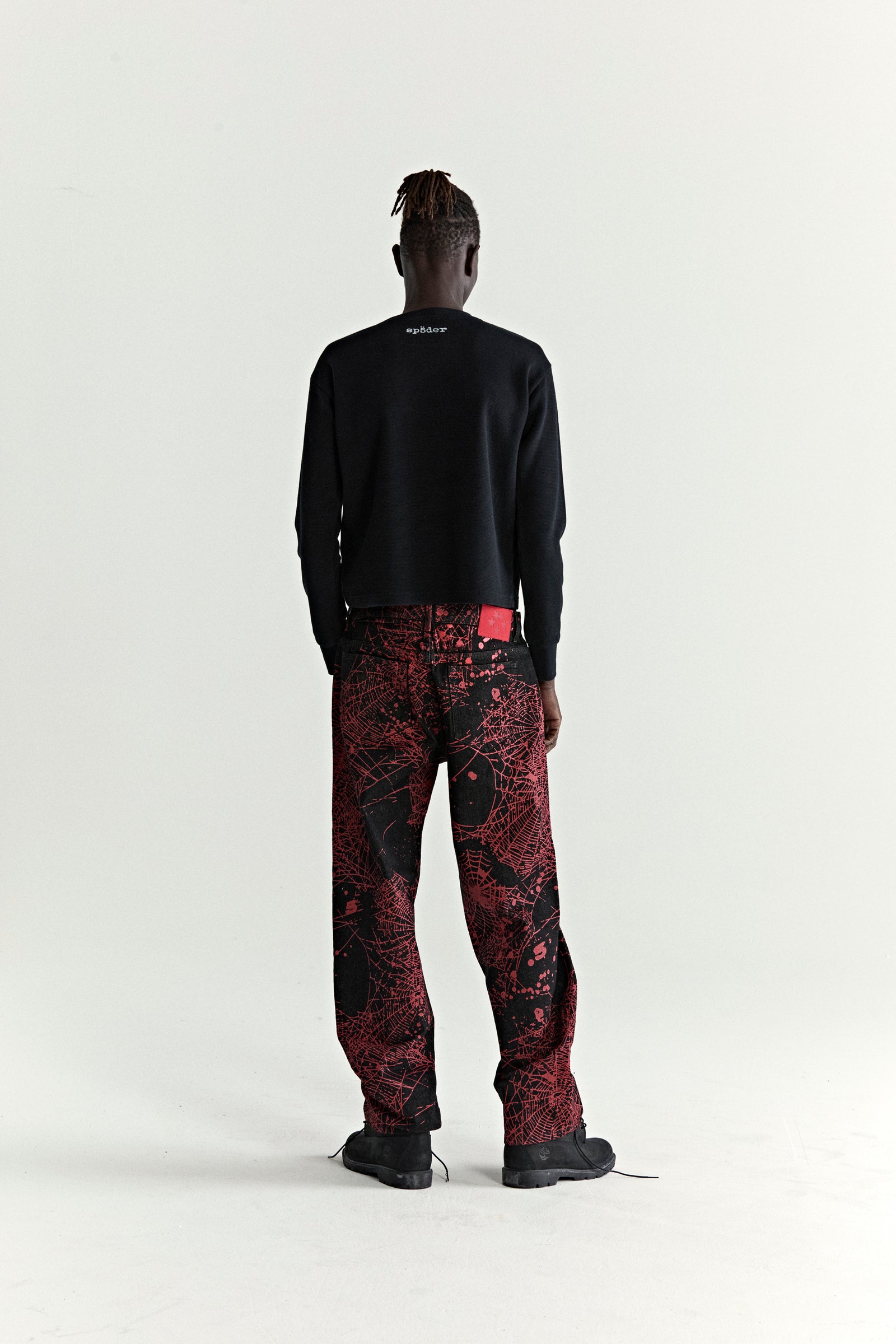 V2 WEB DENIM: Black denim pants with all-over red web print, straight leg fit, and a branded leather patch.