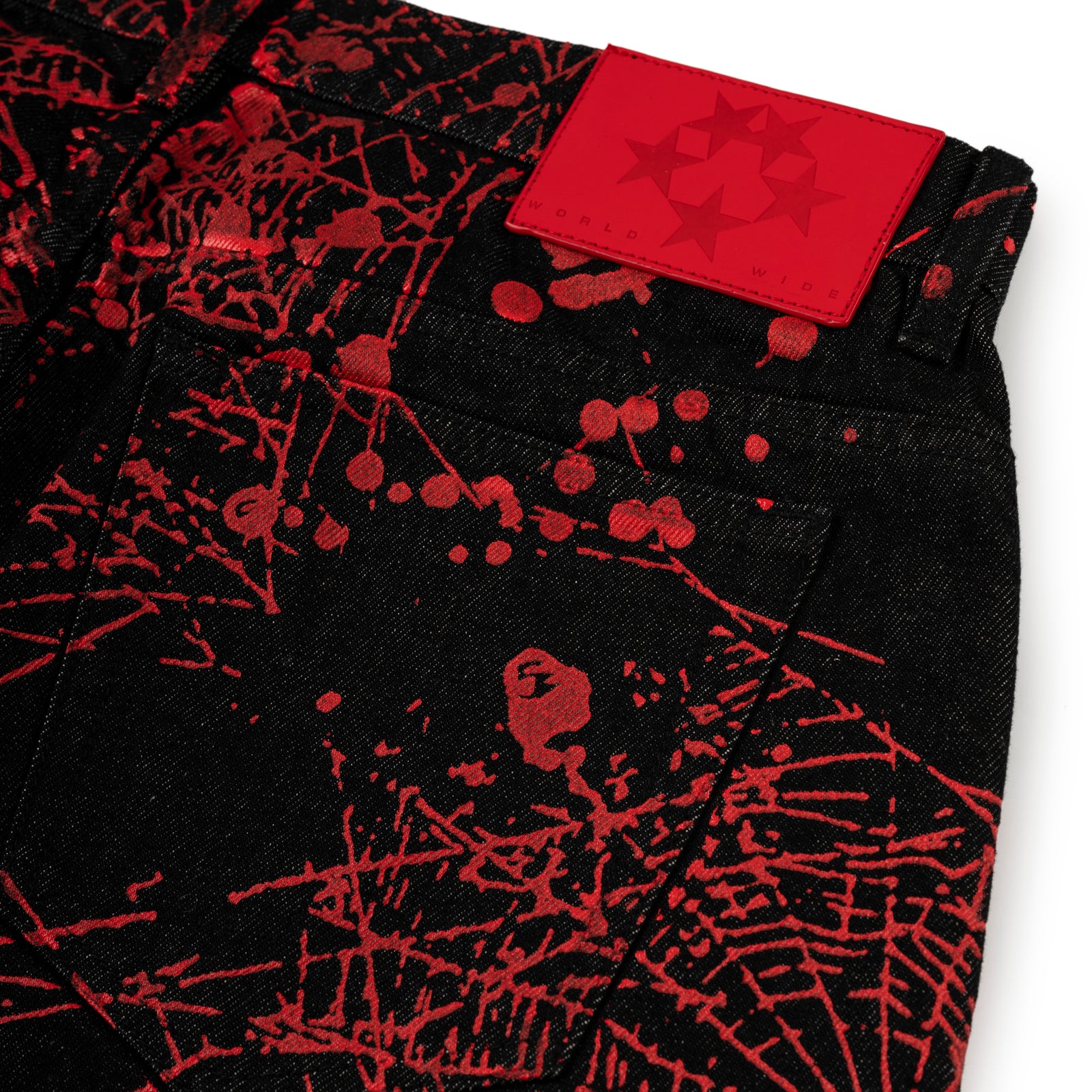 Black denim pants with red web print, back pocket, and red leather branded patch.