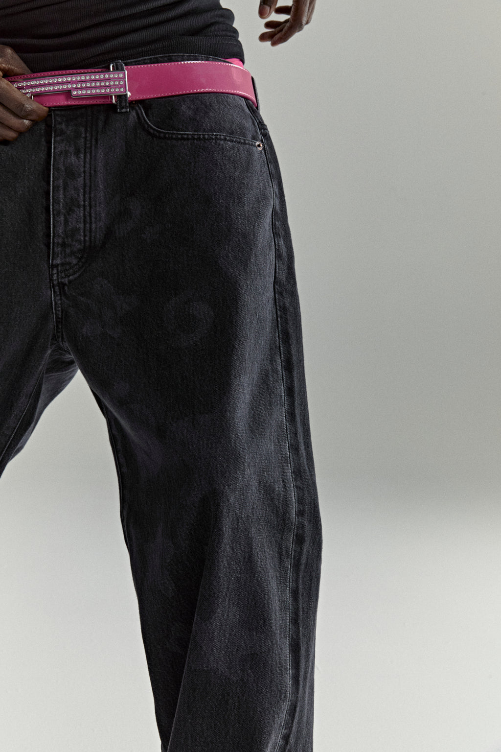 BELUGA DENIM faded wash black jeans with a pink belt and branded hardware.