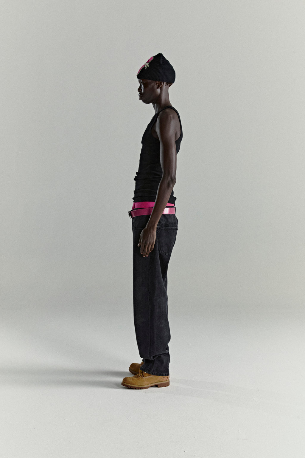 BELUGA DENIM faded wash black jeans with a pink belt, worn by a model in profile.