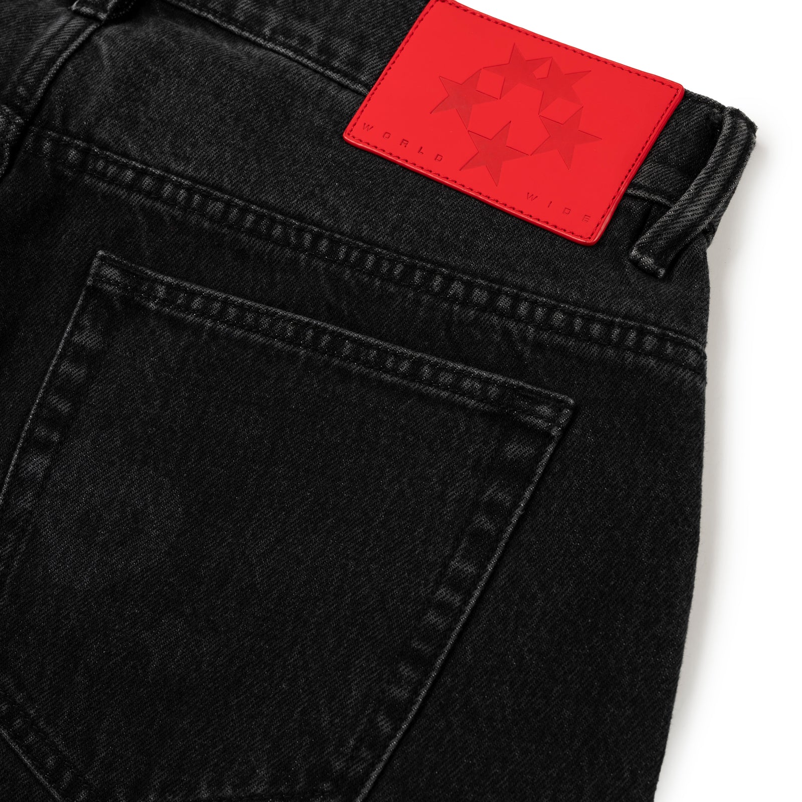 BELUGA DENIM faded black jeans with a red leather back patch featuring stars and "WORLD WIDE".