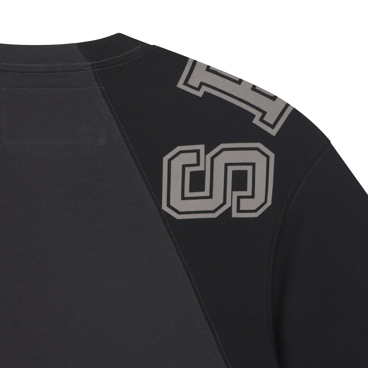 Black cotton crew neck tee featuring color-block panels and collegiate-style grey graphic print on the shoulder.