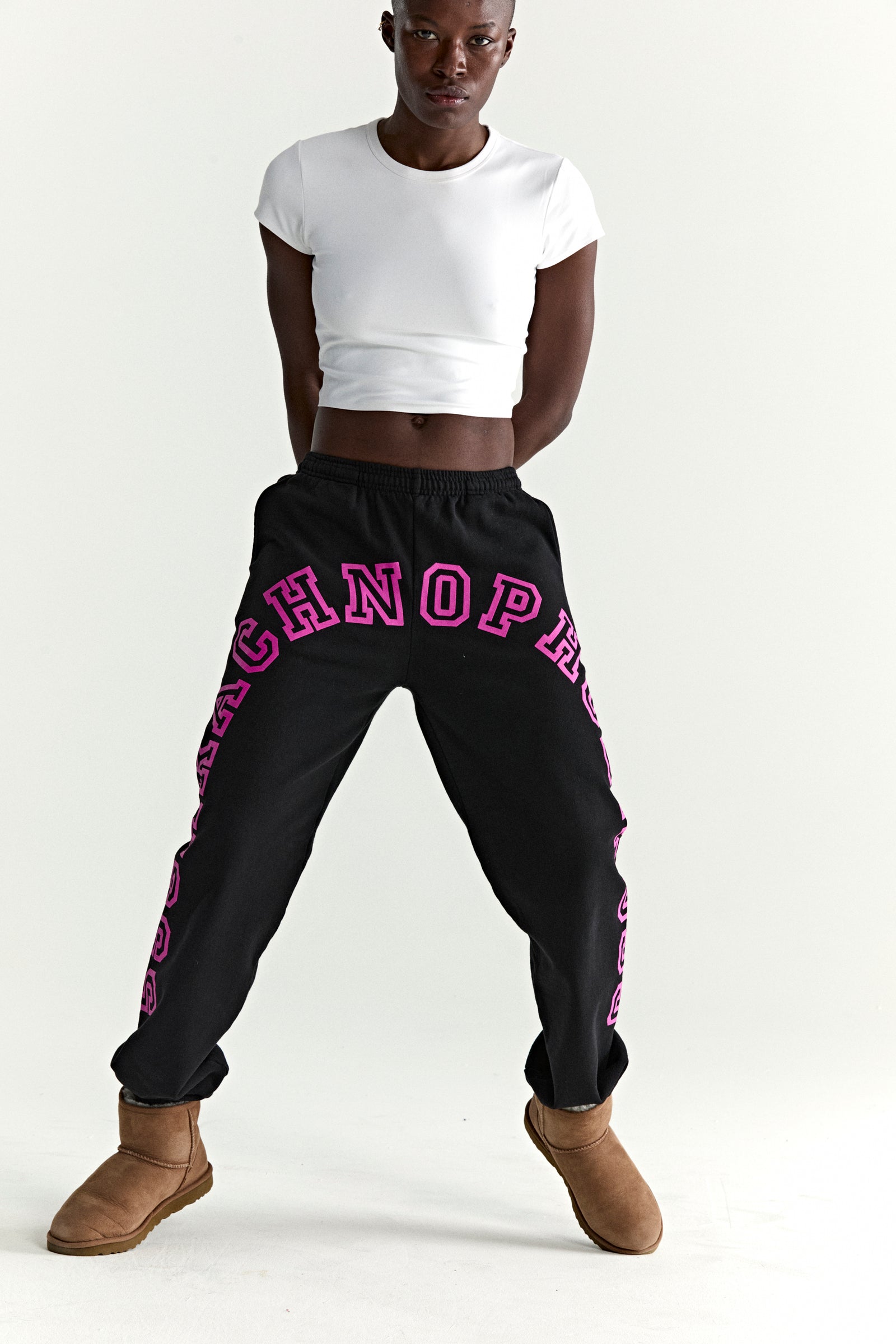 Black ARACH SWEATPANTS with arched pink puff print text, elasticized waistband, and cuffs, worn by a model.