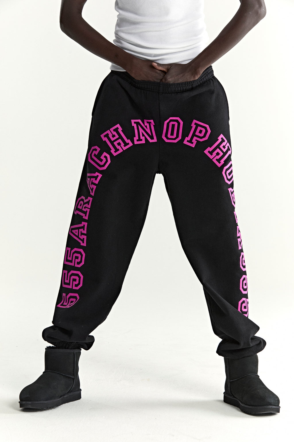 Black cotton fleece sweatpants with arched pink puff print text along crotch and leg, elasticized cuffs.