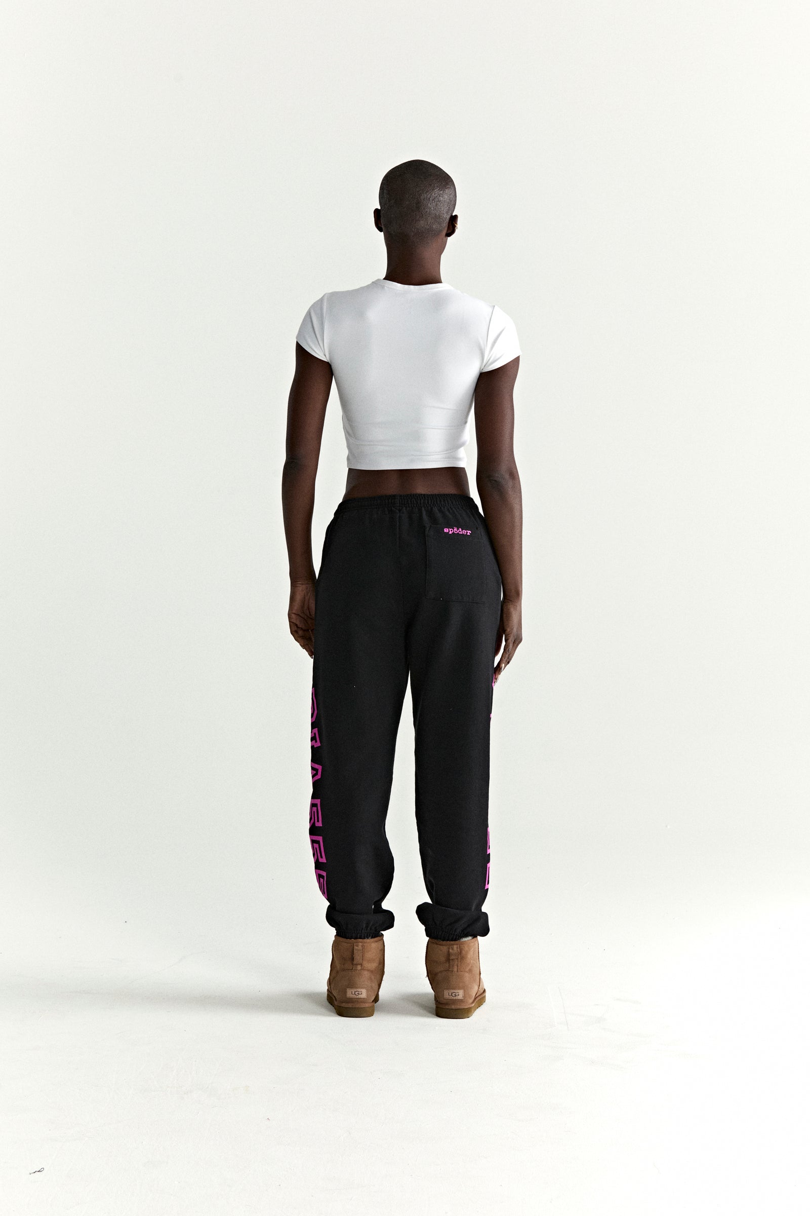 Black ARACH SWEATPANT, 100% cotton fleece, with pink arched text print along crotch and leg.