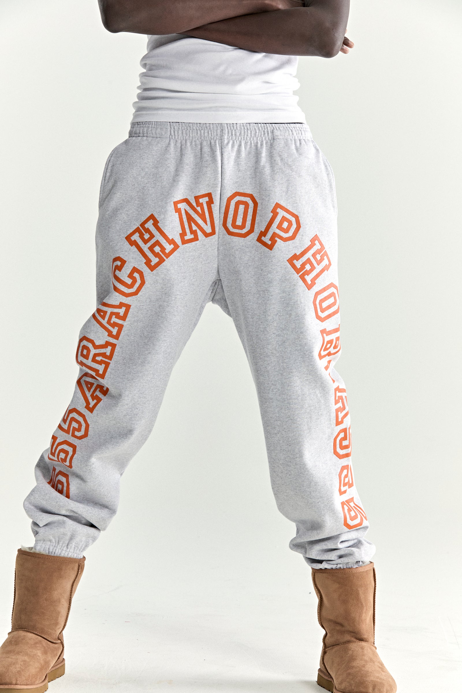 Gray 13oz cotton fleece sweatpants with orange arched text puff print, drawstring, and elasticized cuffs.