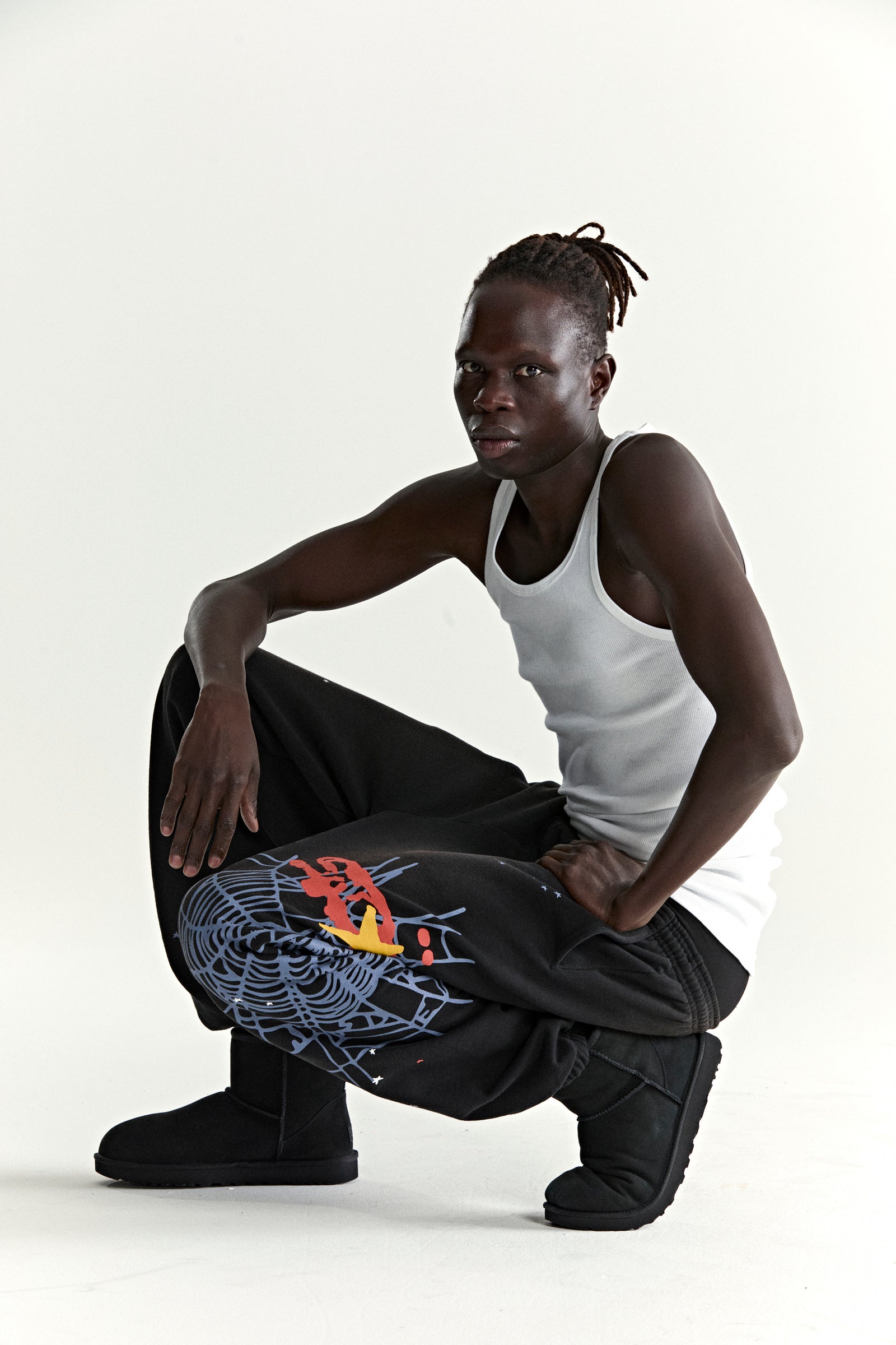 Black HEAVY WEB SWEATPANTS with SP5DER web graphic and scattered stars, worn by a model.