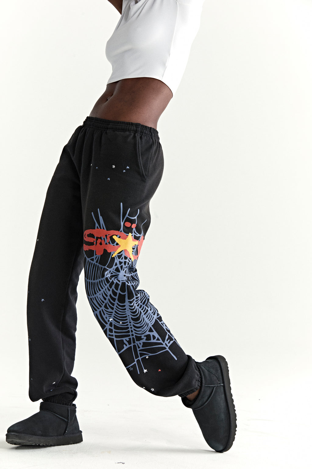Black 13oz cotton fleece sweatpants with red SP5DER puff print, blue web graphic, and scattered stars.