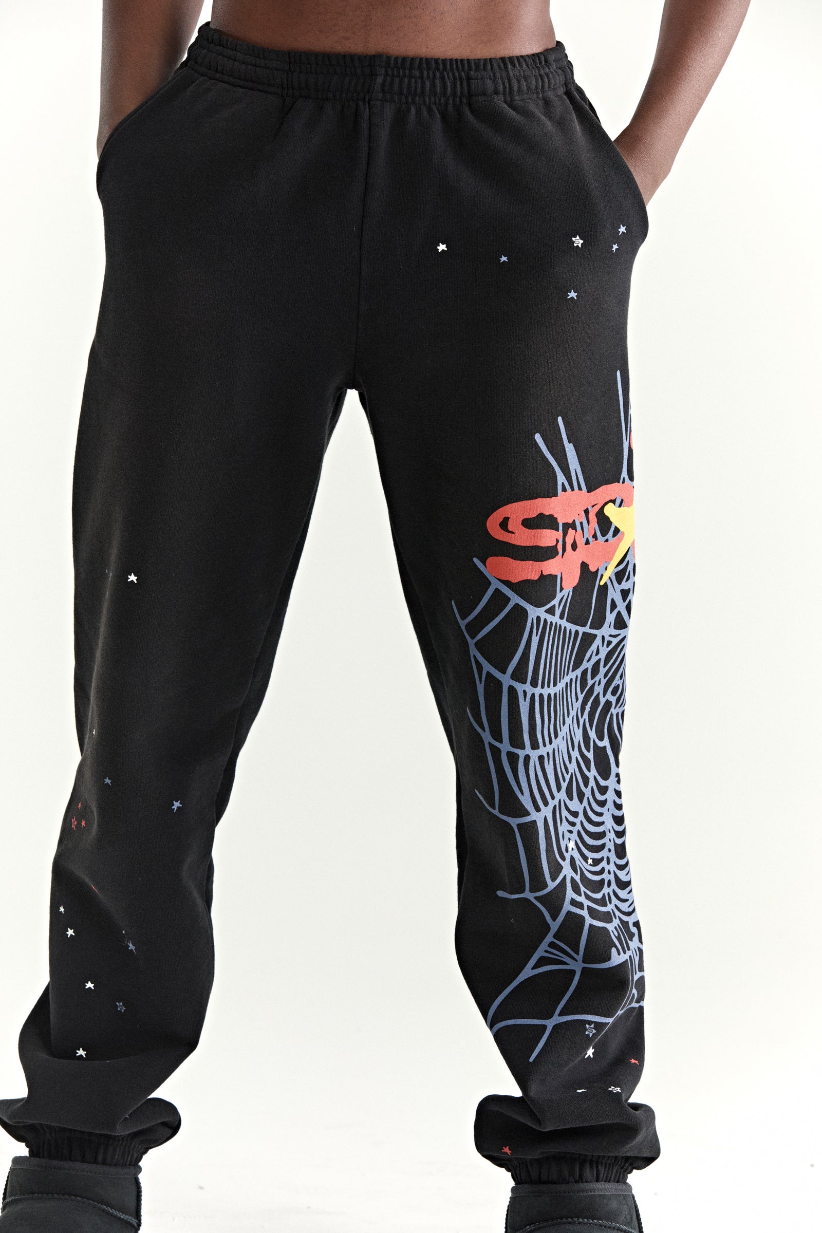 Black 13oz cotton fleece sweatpants with SP5DER web graphic, scattered stars, and elasticized cuffs.