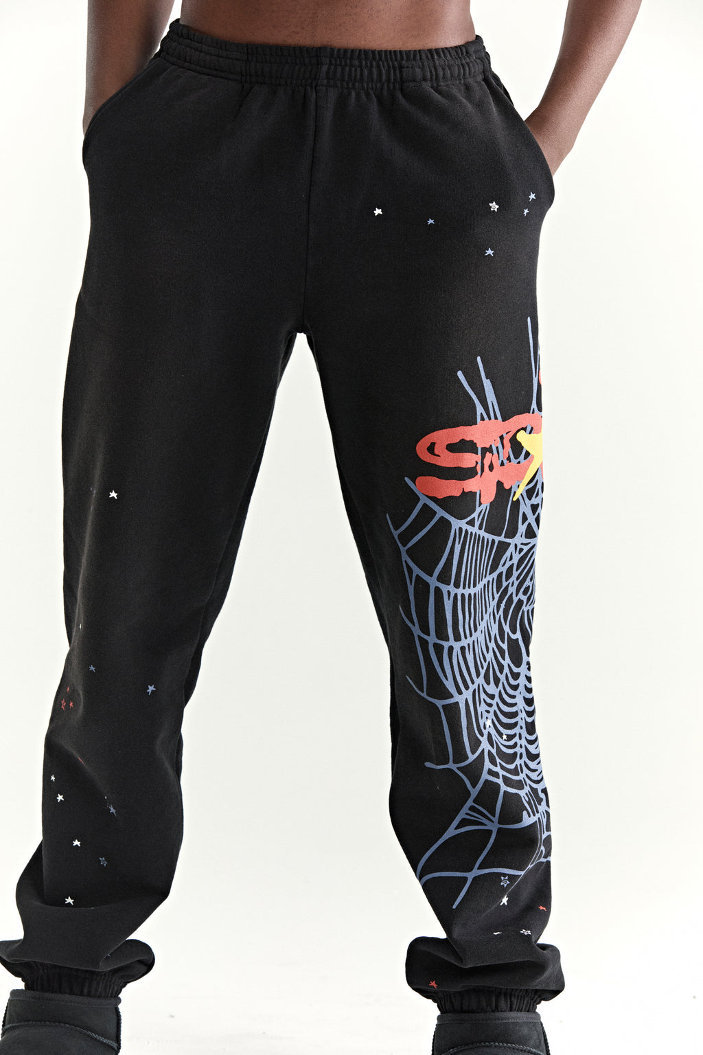 Black 13oz cotton fleece sweatpants with SP5DER web graphic, scattered stars, and elasticized cuffs.