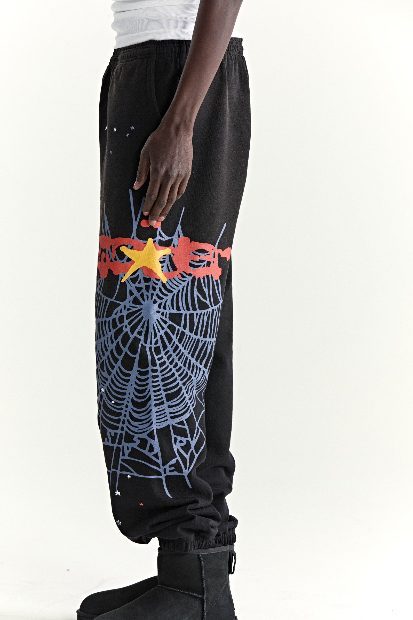 Black 100% cotton fleece sweatpants with blue spider web, red SP5DER, and yellow star graphic.