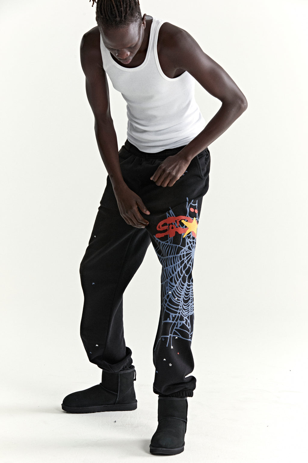 Black HEAVY WEB SWEATPANTS with colorful SP5DER web graphic and scattered stars on leg.