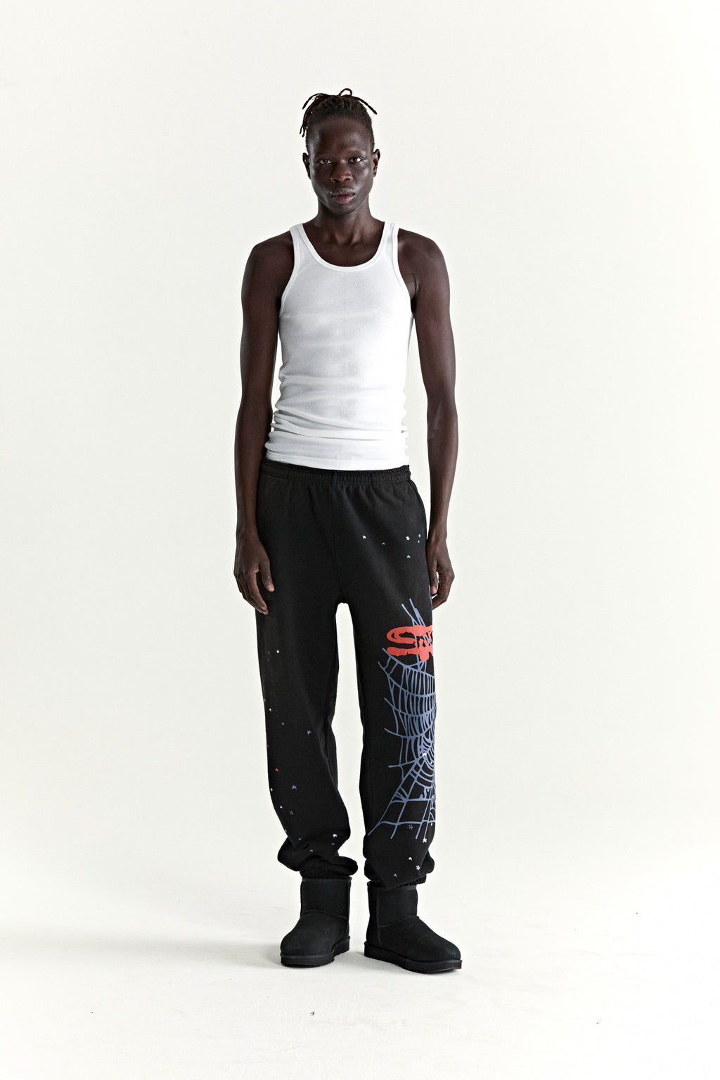 Black HEAVY WEB SWEATPANT with red SP5DER graphic, blue web, and scattered stars, worn by a model.