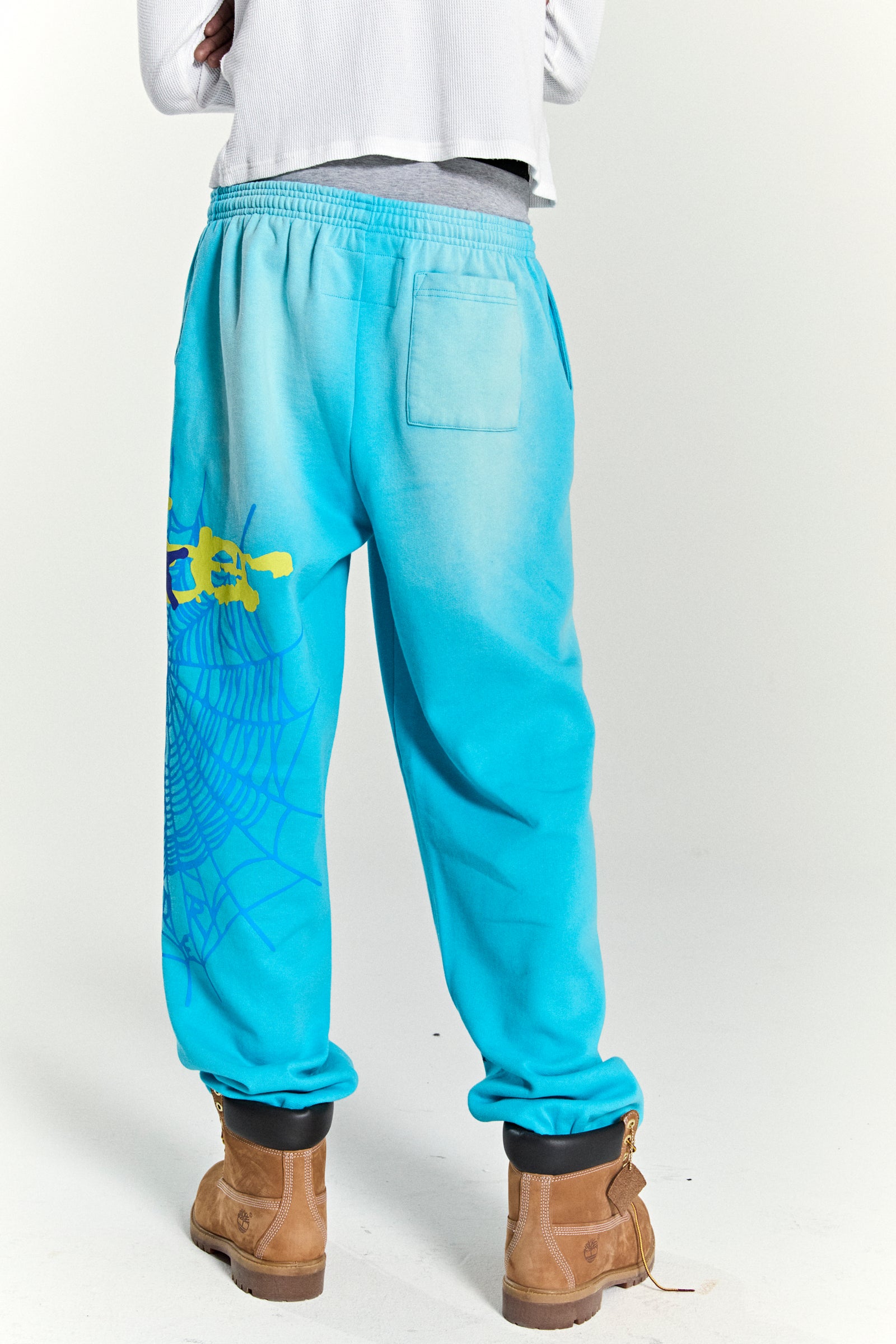 Blue cotton fleece sweatpants with yellow SP5DER web graphic and scattered stars, elasticized cuffs.