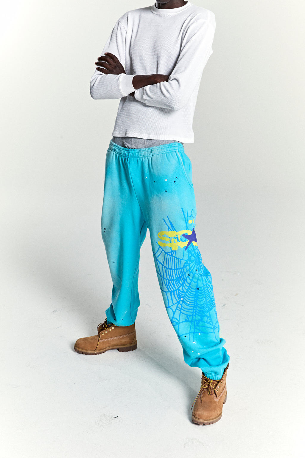 Turquoise HEAVY WEB SWEATPANT with yellow SP5DER web graphic and scattered stars.