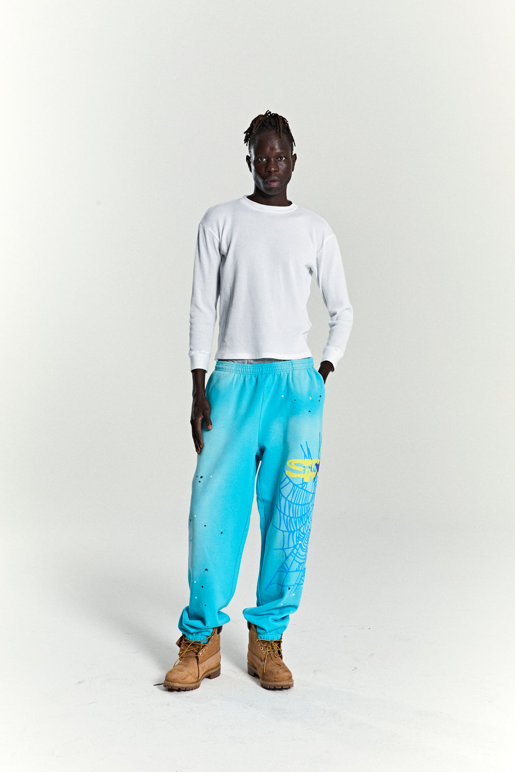 Blue HEAVY WEB SWEATPANT with yellow SP5DER web graphic, scattered stars, and elasticized cuffs.