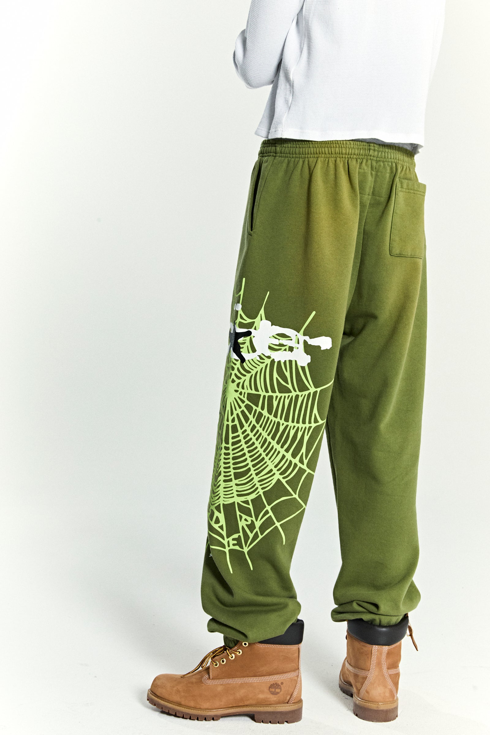 Olive green cotton fleece sweatpants with a neon green SP5DER web graphic and scattered stars.