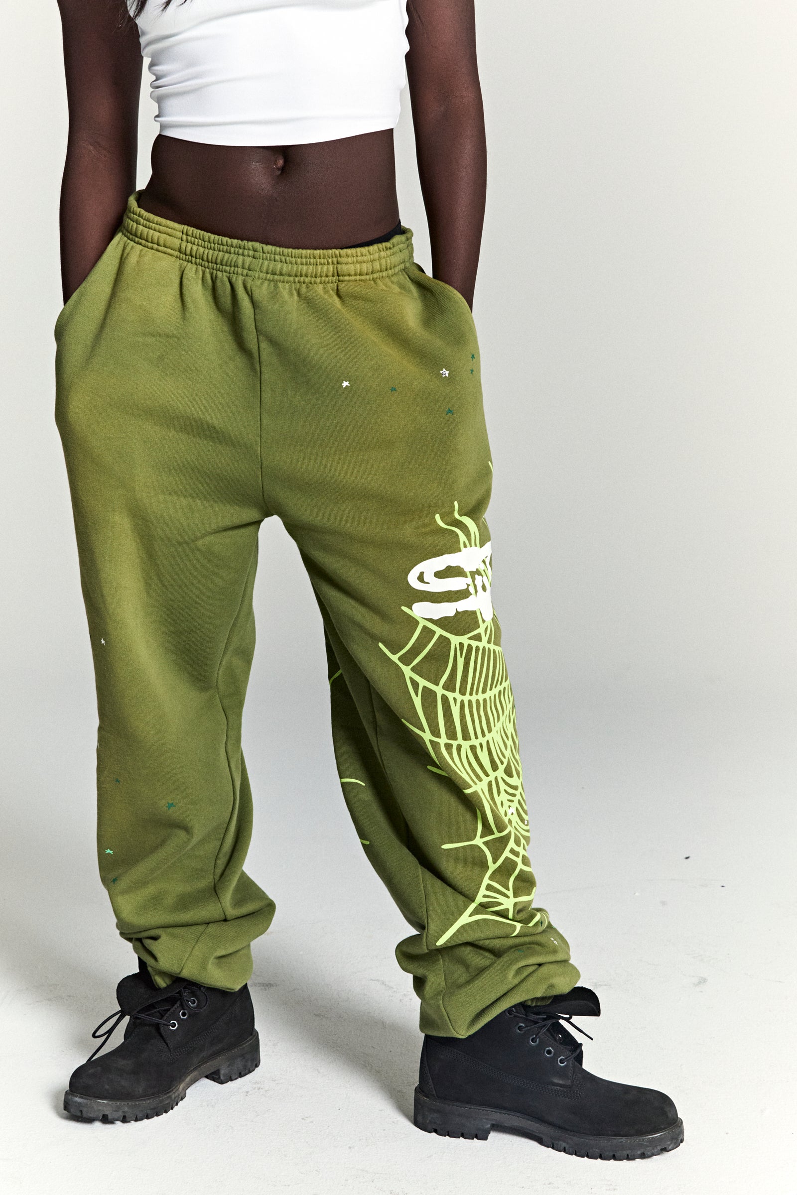 Olive green fleece sweatpants with white SP5DER web graphic and scattered star print.