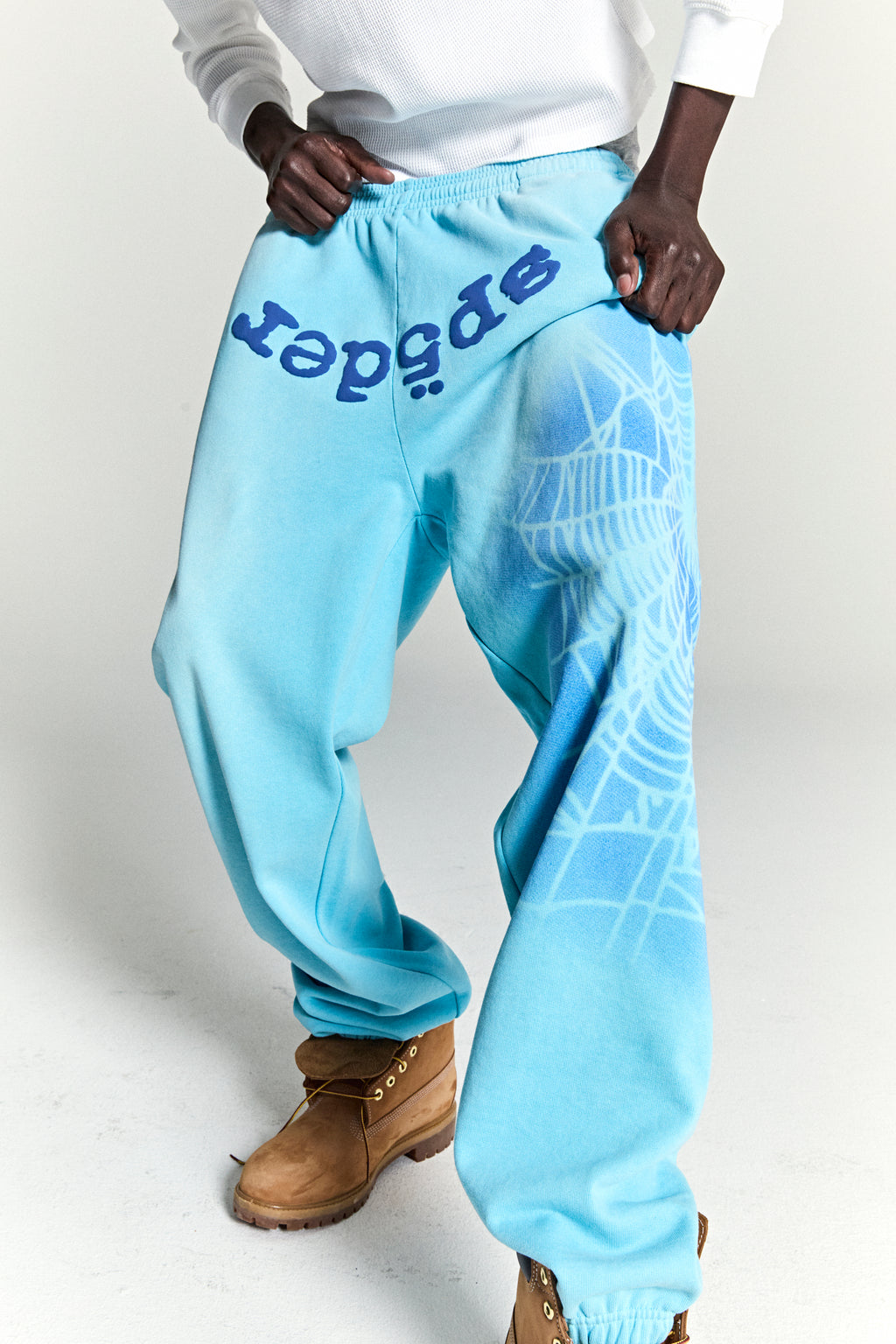 Light blue cotton fleece sweatpants with "SP5DER" text and spray web design.