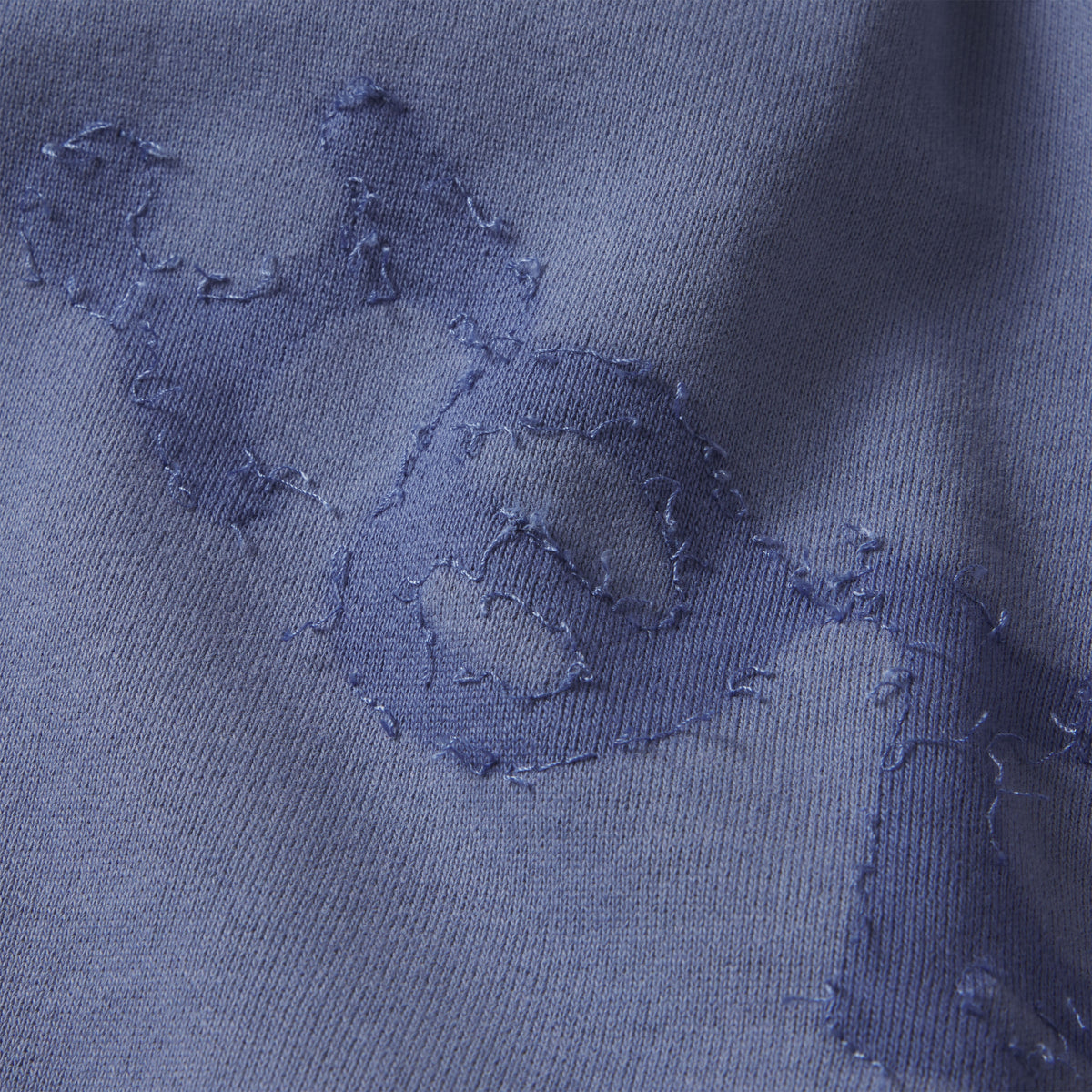 Blue cotton fleece sweatpants featuring distressed graphic design applique details.