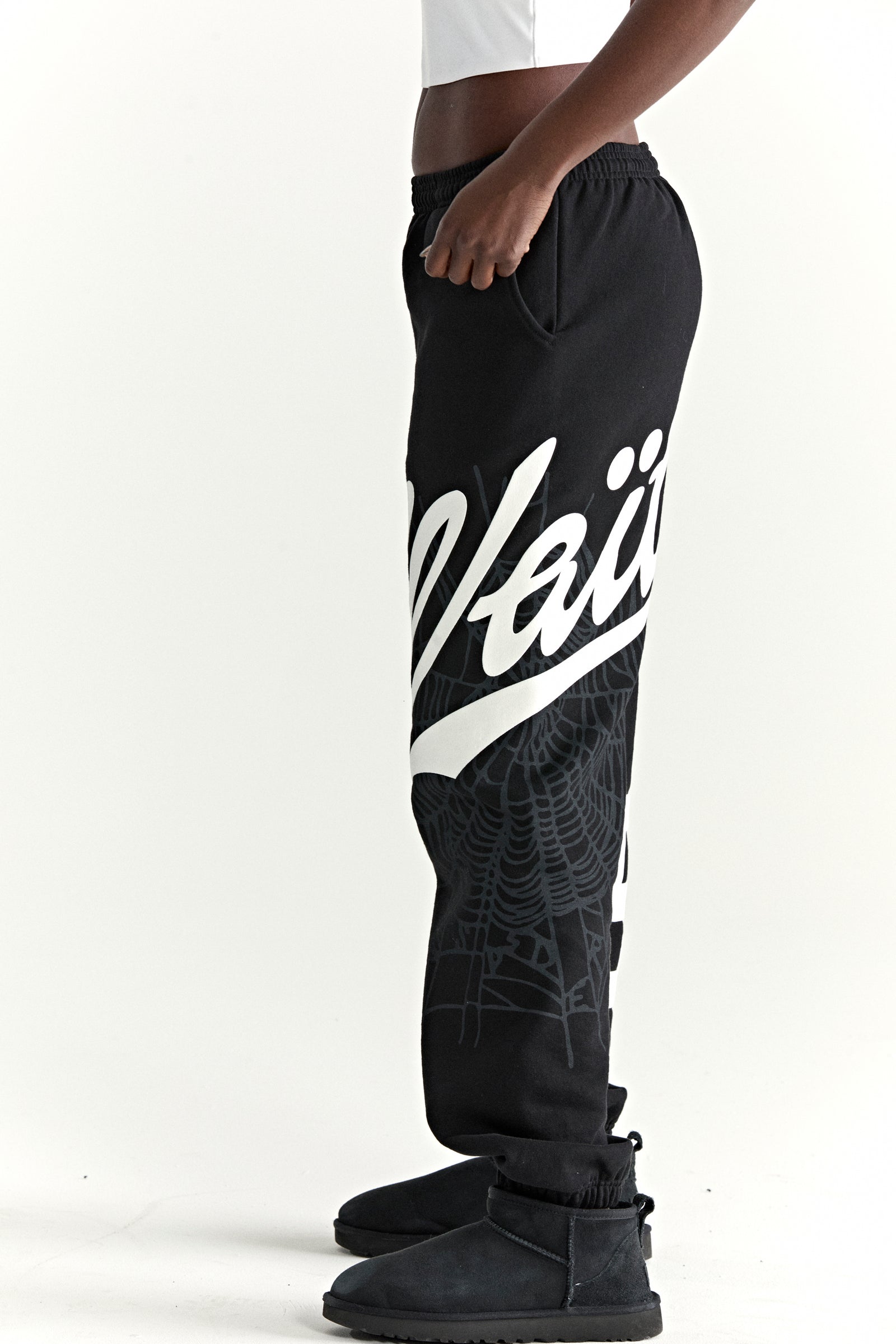 Black cotton fleece sweatpants with white "Wait" script and spiderweb print, elasticized cuffs.
