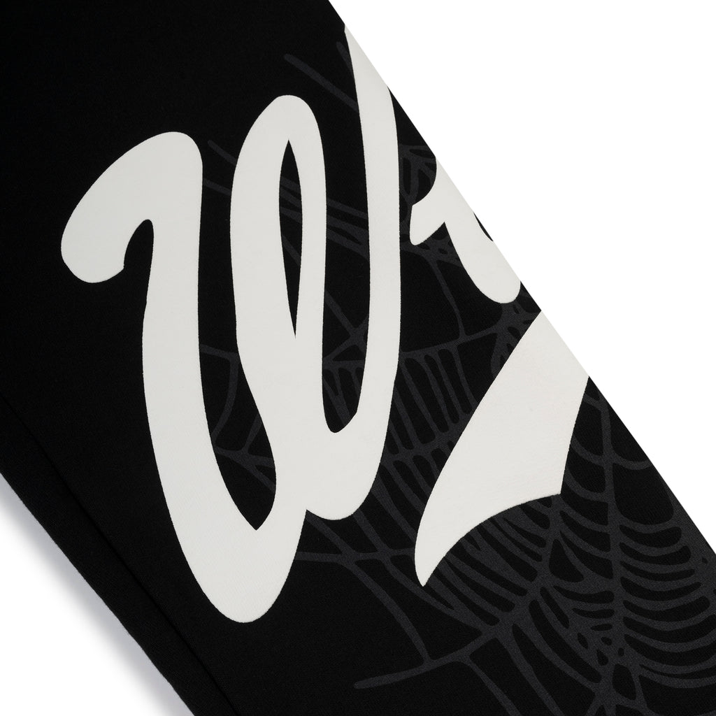 Black cotton fleece sweatpant with white "Wait" script and subtle spiderweb print.