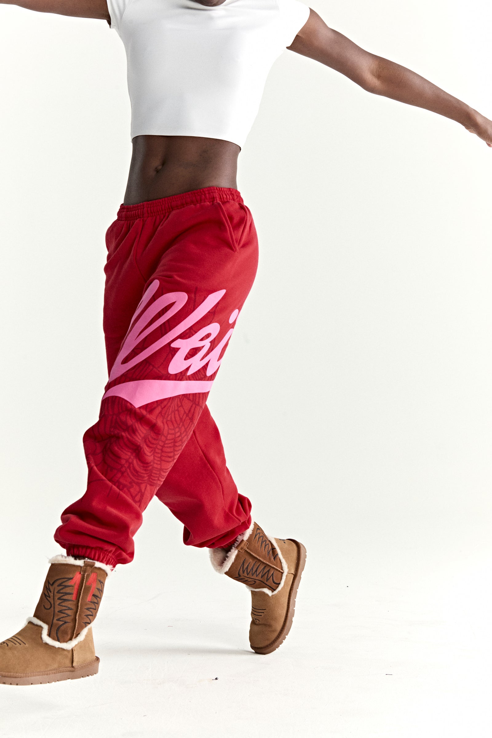 Red cotton fleece sweatpants with pink 'Wait' script and web print, elasticized cuffs.