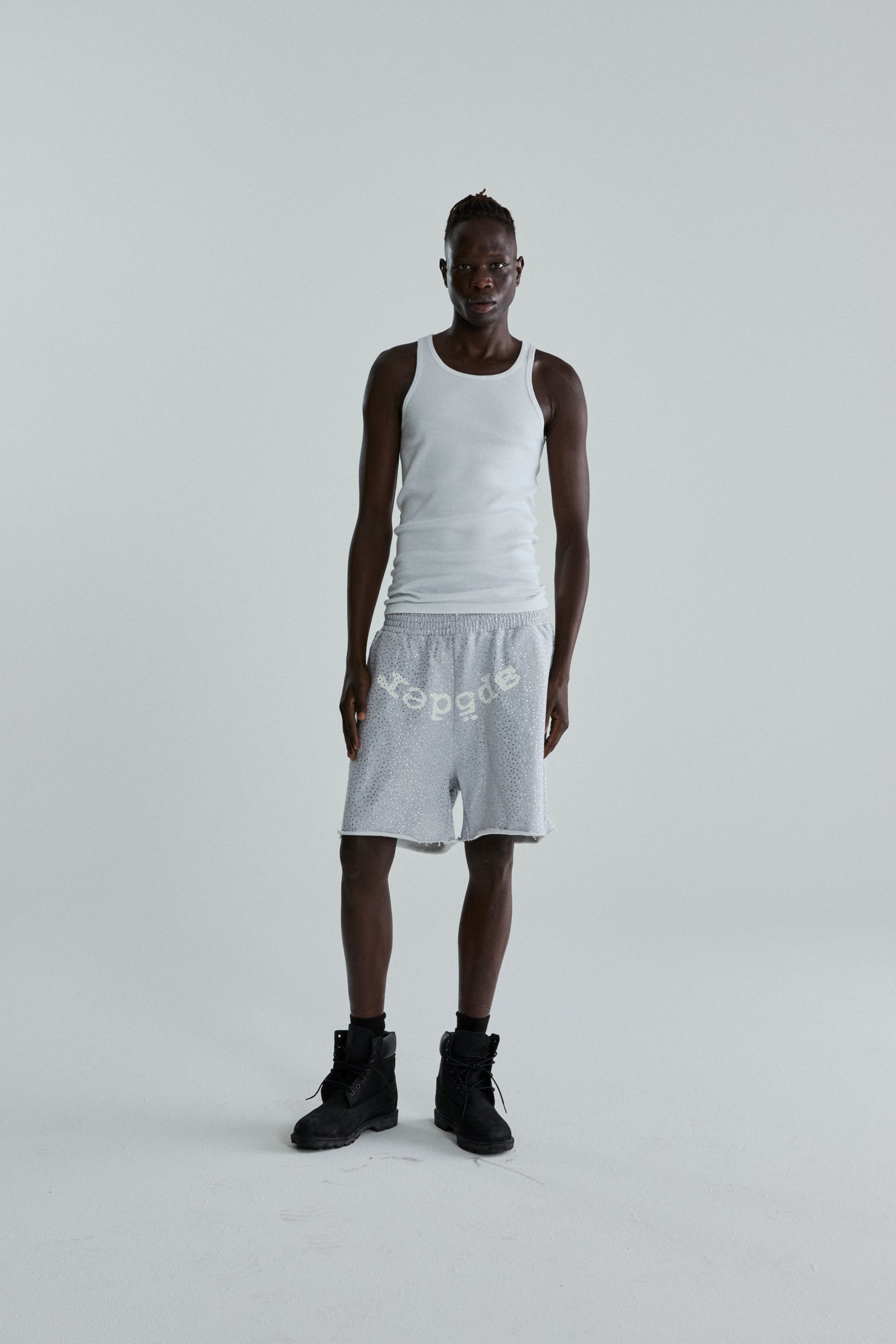 Man in VVS SWEATSHORT: grey 13oz cotton fleece with tonal rhinestones and "SP5DER" text.