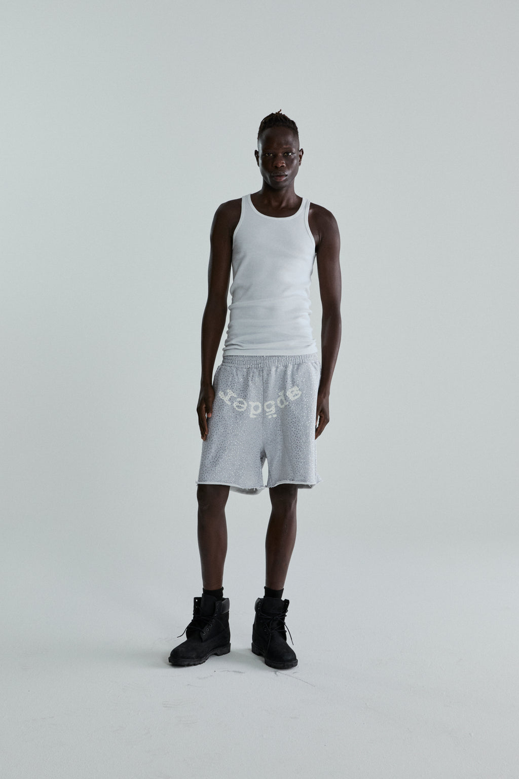 Man in VVS SWEATSHORT: grey 13oz cotton fleece with tonal rhinestones and "SP5DER" text.