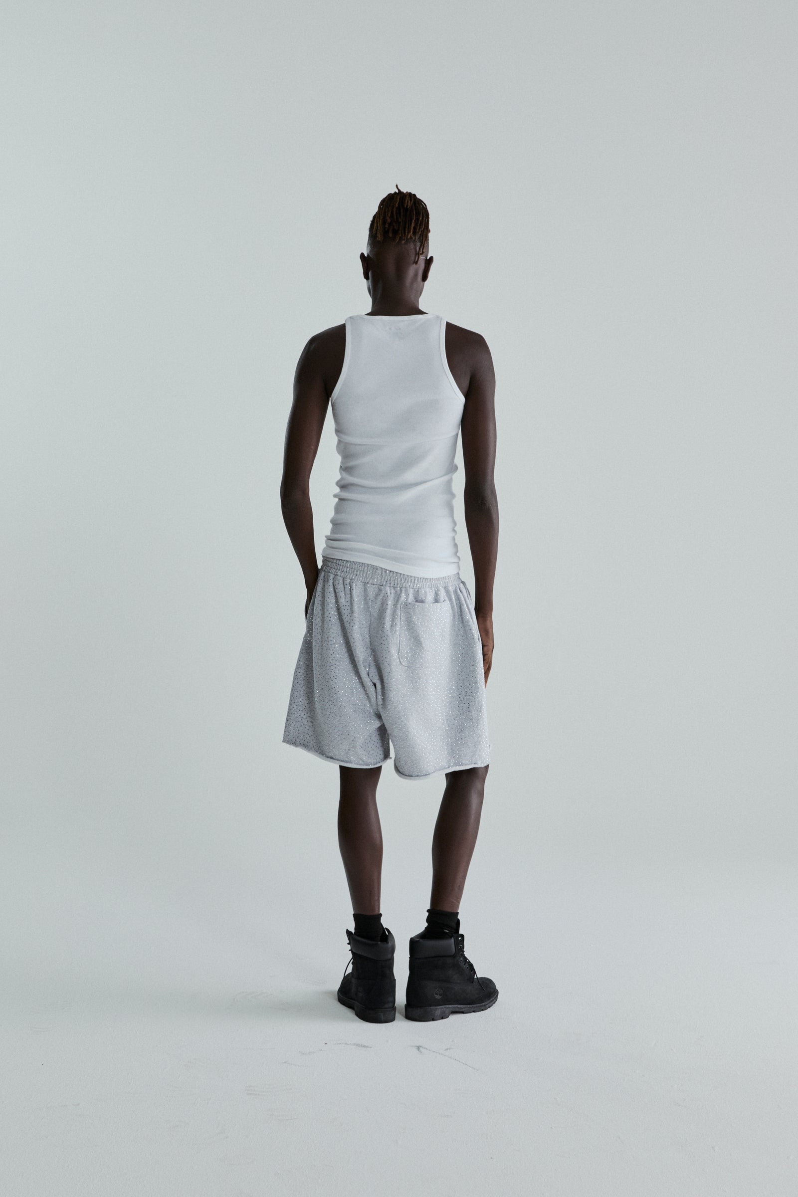 Model wearing VVS SWEATSHORT: gray 13oz cotton fleece shorts with tonal rhinestone application and raw hem.