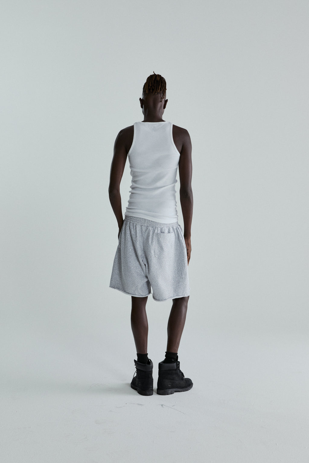 Model wearing VVS SWEATSHORT: gray 13oz cotton fleece shorts with tonal rhinestone application and raw hem.
