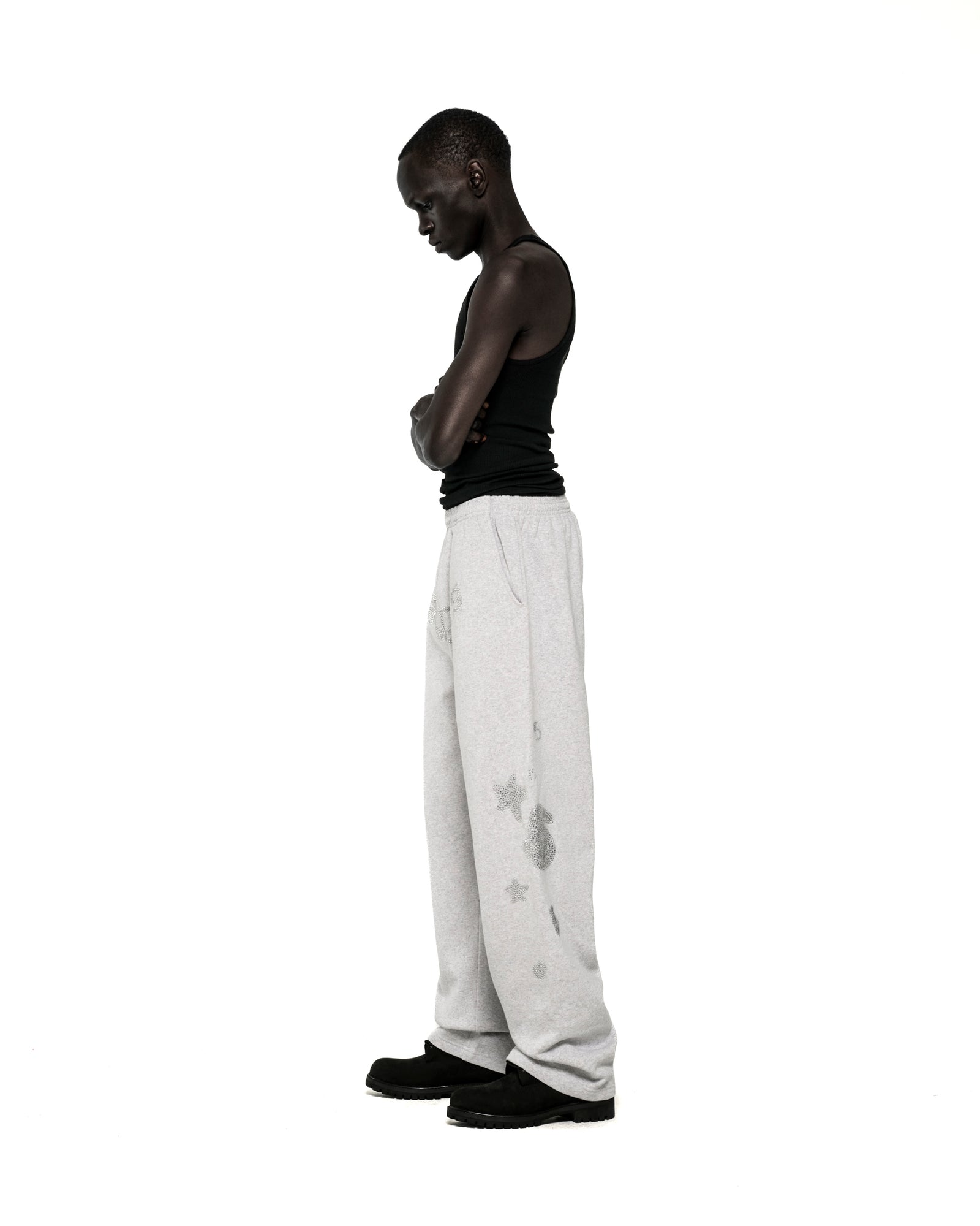 Light grey wide-leg sweatpants with rhinestone 'SP5DER' text, '5', and star designs.