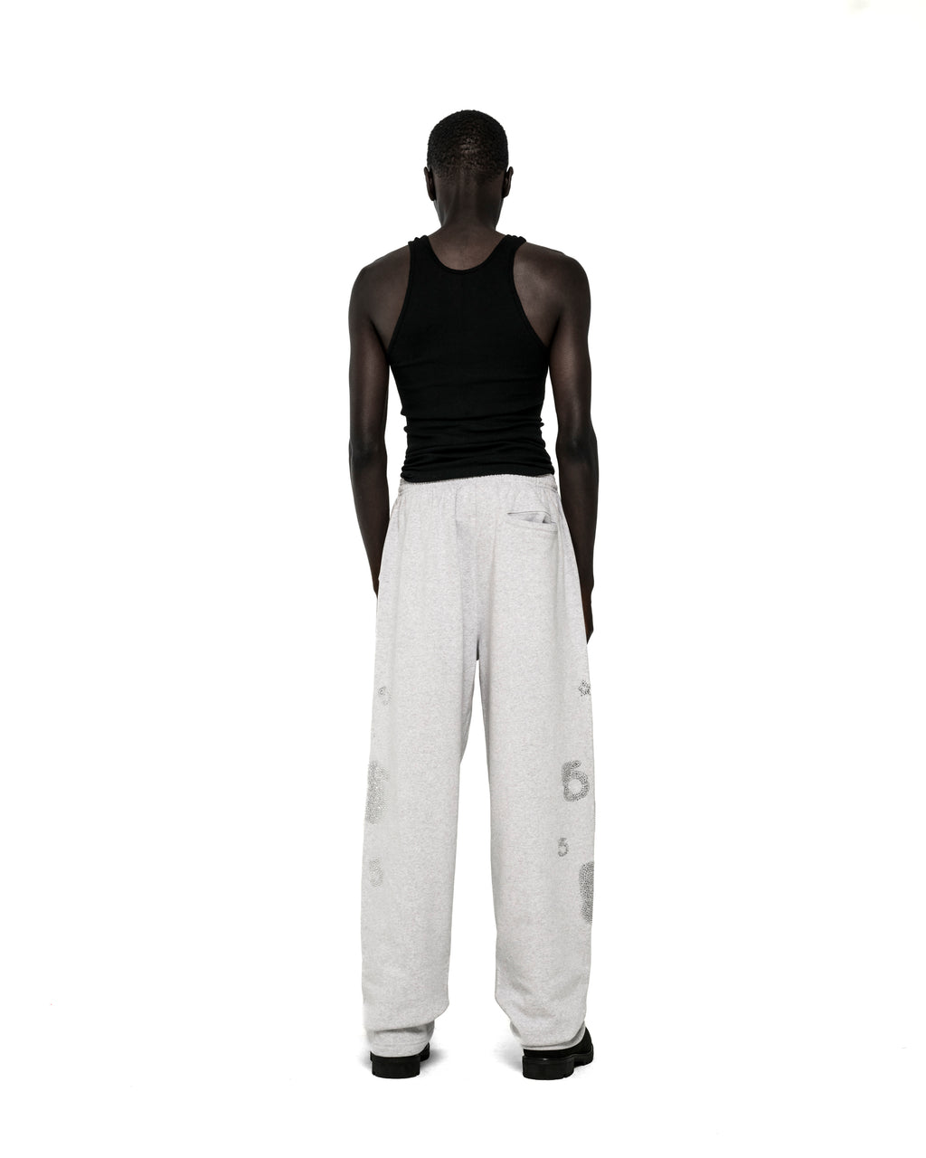 Model from behind wearing light grey RHINESTONE BELUGA V2 WIDE LEG SWEATPANTS with rhinestone '5' and star designs.