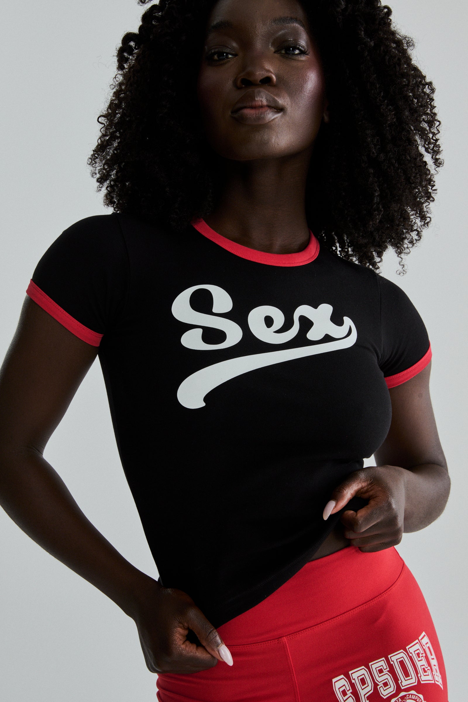 Black cropped cotton/spandex SEX BABY TEE with white graphic print and red ribbed trim.