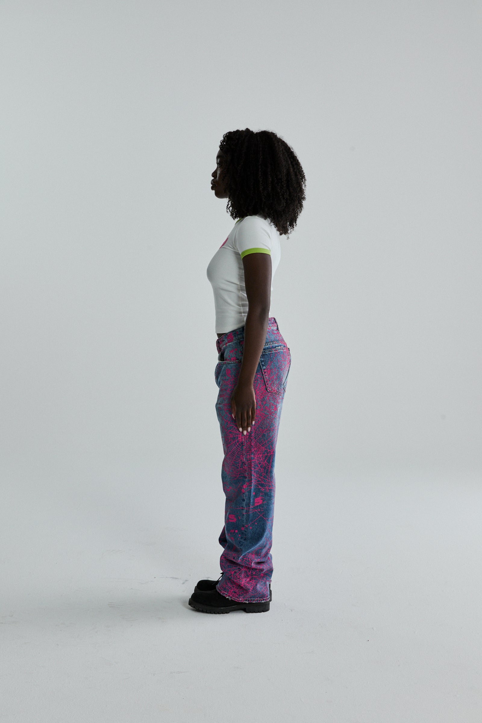 Woman in white cropped SEX BABY TEE with green trim, paired with blue and pink graphic print jeans.